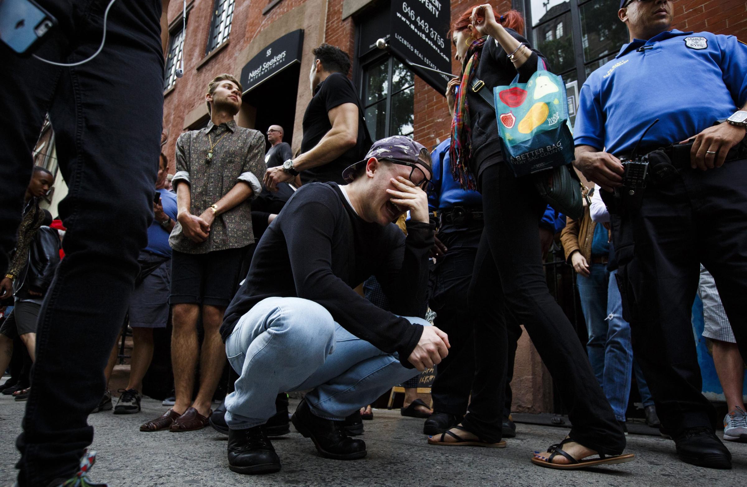 Taylor Forrest (C), of Orlando, Florida, cries on the sidewalk near a memorial for the victims of a mass shooting at a gay club in Orlando outside of the Stonewall Inn, a famous gay bar, in New York City on June 13, 2016.