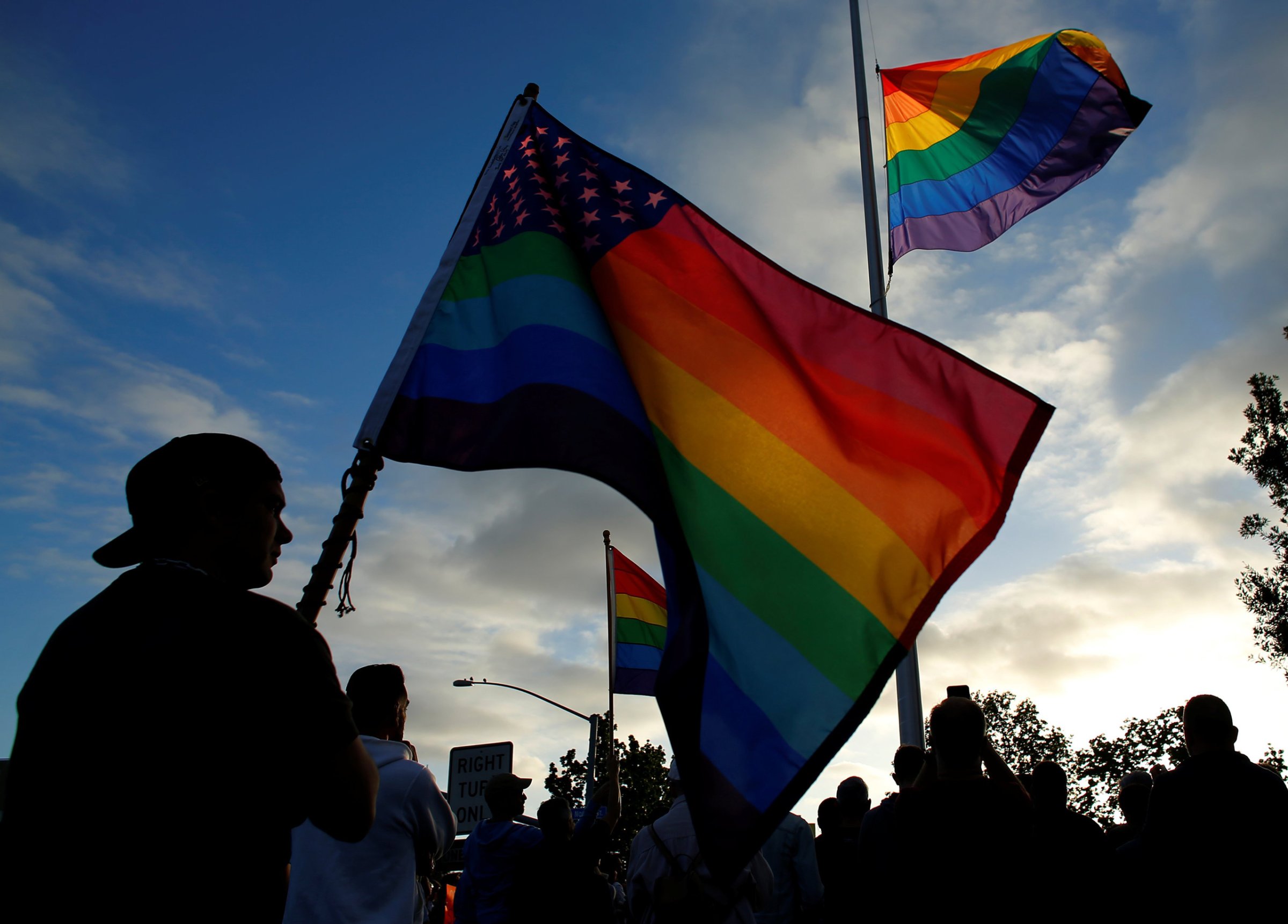 Mourners gather under an LGBT pride flag flying at half-mast for a candlelight vigil in remembrance for mass shooting victims in Orlando, from San Diego, June 12, 2016.
