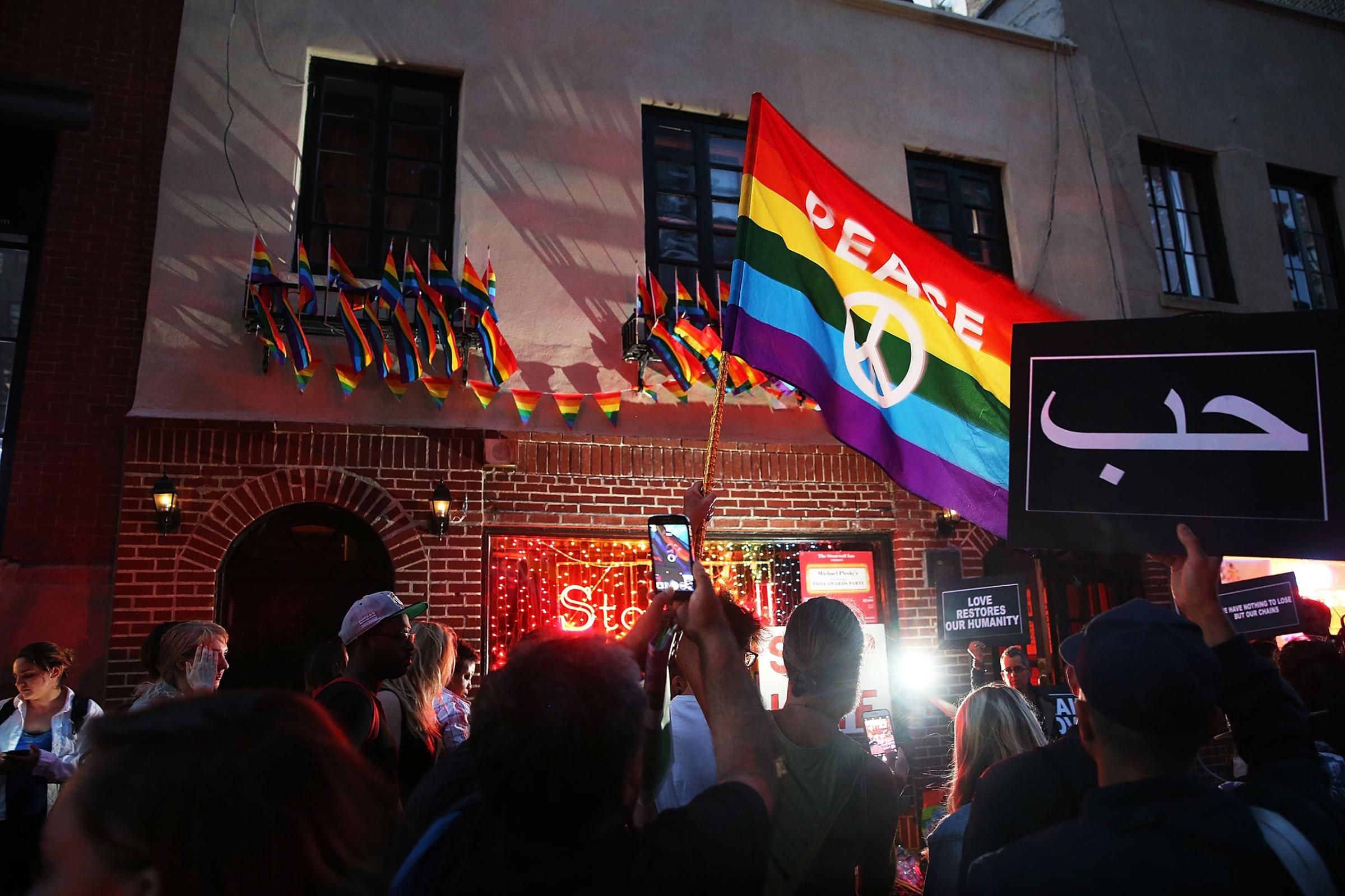 Mourners gather outside of the iconic New York City gay and lesbian bar the Stonewall Inn to light candles,lay flowers and grieve for those killed in Orlando last evening on June 12, 2016.