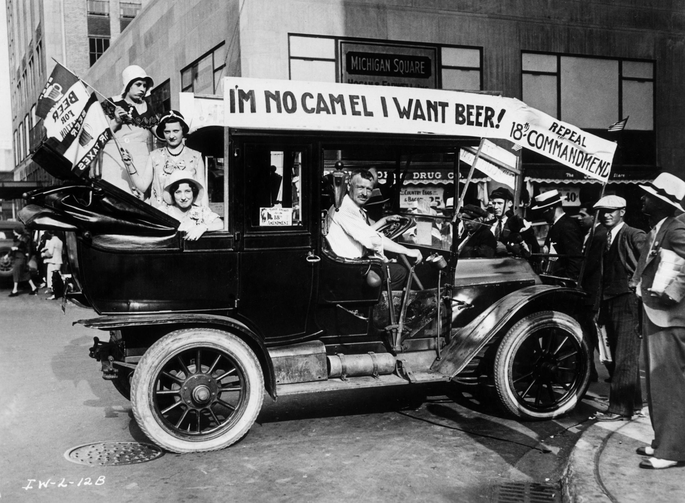 Prohibition protesters parade in a car emblazoned with signs and flags calling for the repeal of the 18th Amendment.