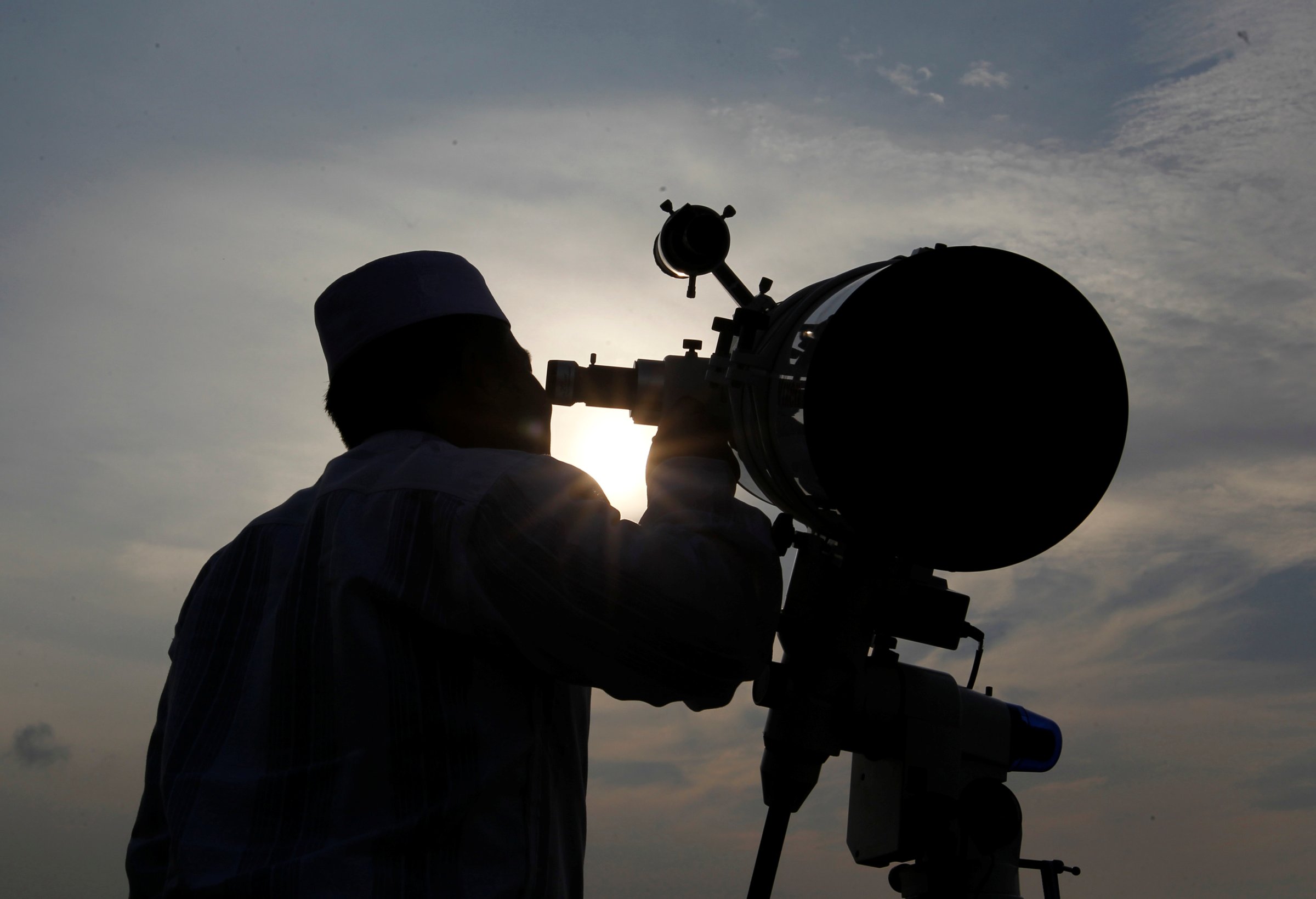 A Muslim man uses a telescope to observe the moon before the Muslim holy month of Ramadan