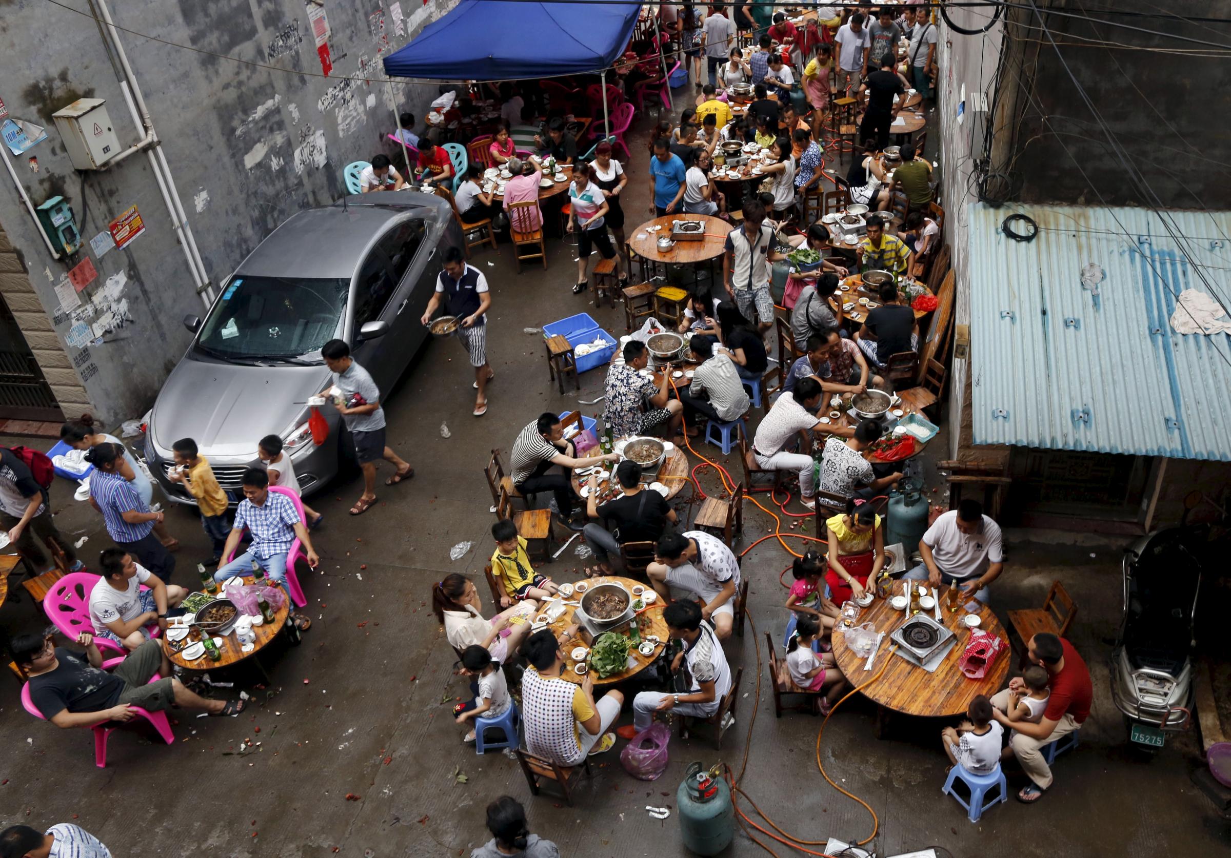 People eat dog meat at a dog meat restaurant district on the day of local dog meat festival in Yulin