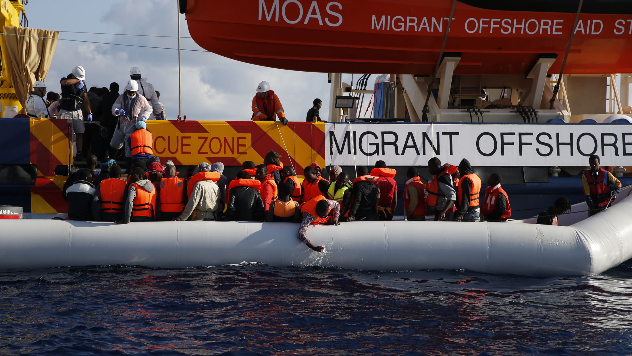 Migrants in a dinghy climb aboard the Migrant Offshore Aid Station (MOAS) ship Topaz Responder, some 20 nautical miles off the coast of Libya, June 23, 2016. (Darrin Zammit Lupi—Reuters)