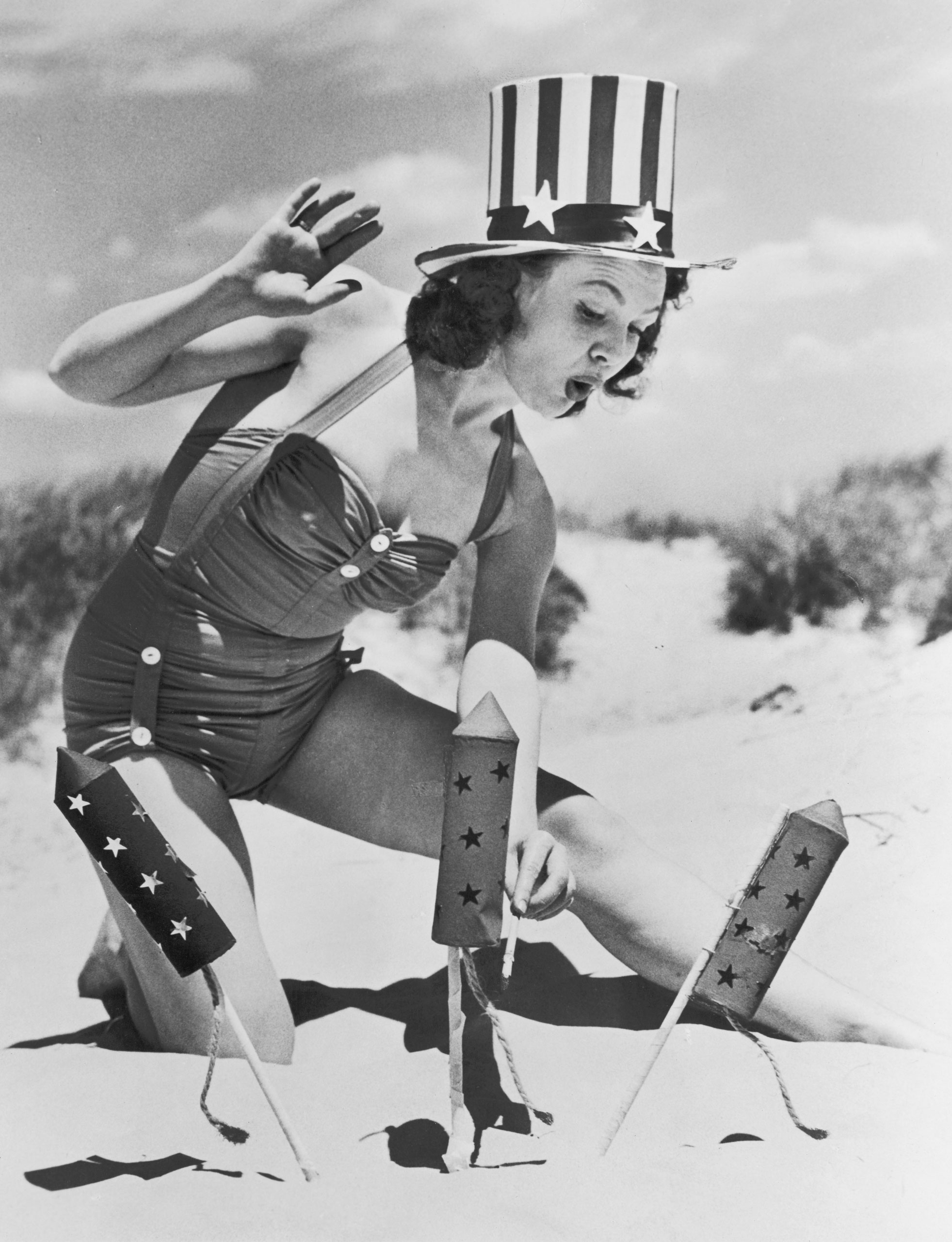 Actress Louise Synder wearing a patriotic hat to light fireworks on the beach during Fourth of July celebrations, circa 1950.