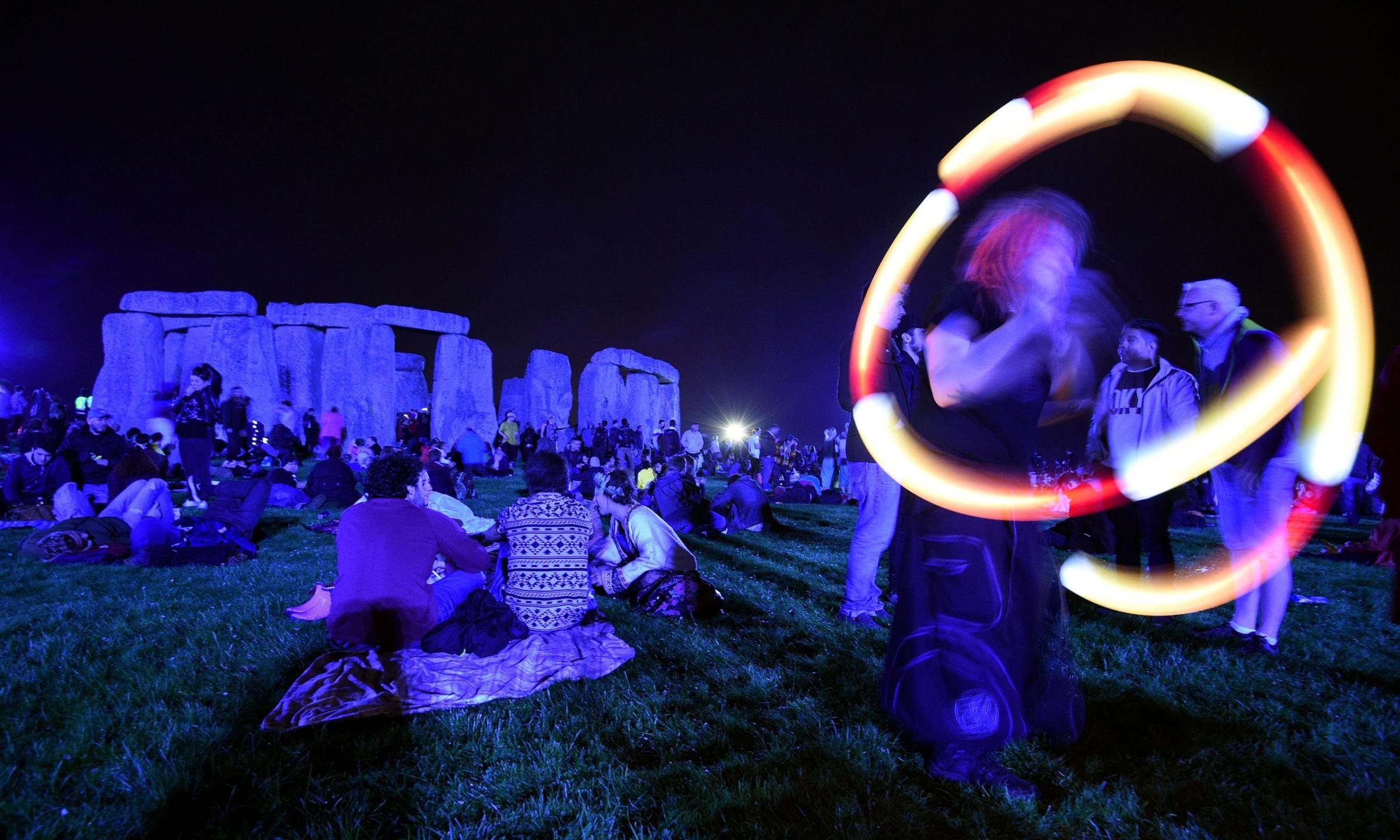 A poi performer spins light balls as people gather at Stonehenge in Wiltshire, England to see in the new dawn after this year's Summer Solstice on June 21, 2016.