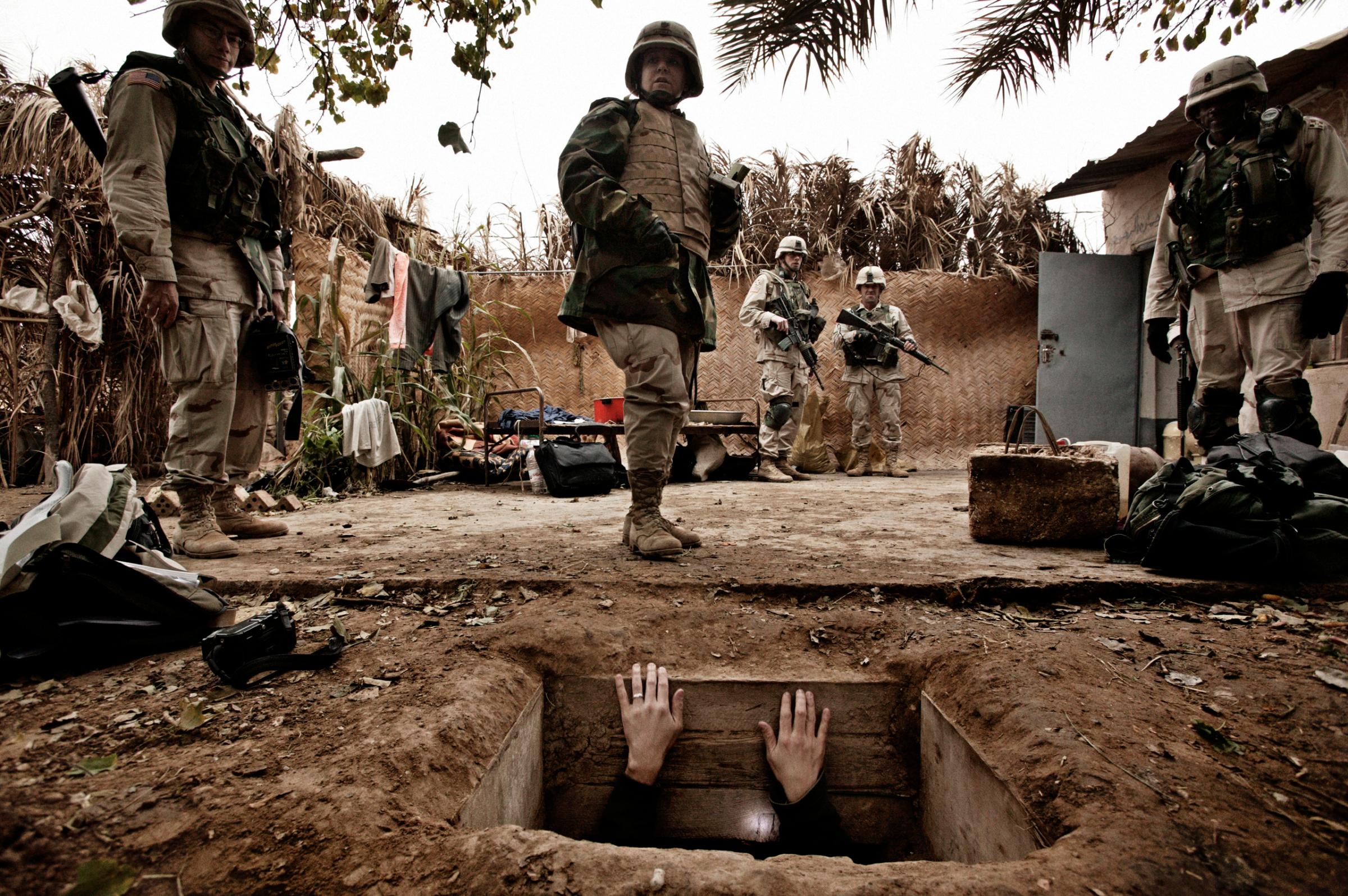 A jounalist climbs out of the hole where toppled dictator Saddam Hussein was captured in Ad Dawr, Iraq, near his hometown of Tikrit, Dec. 15, 2003.