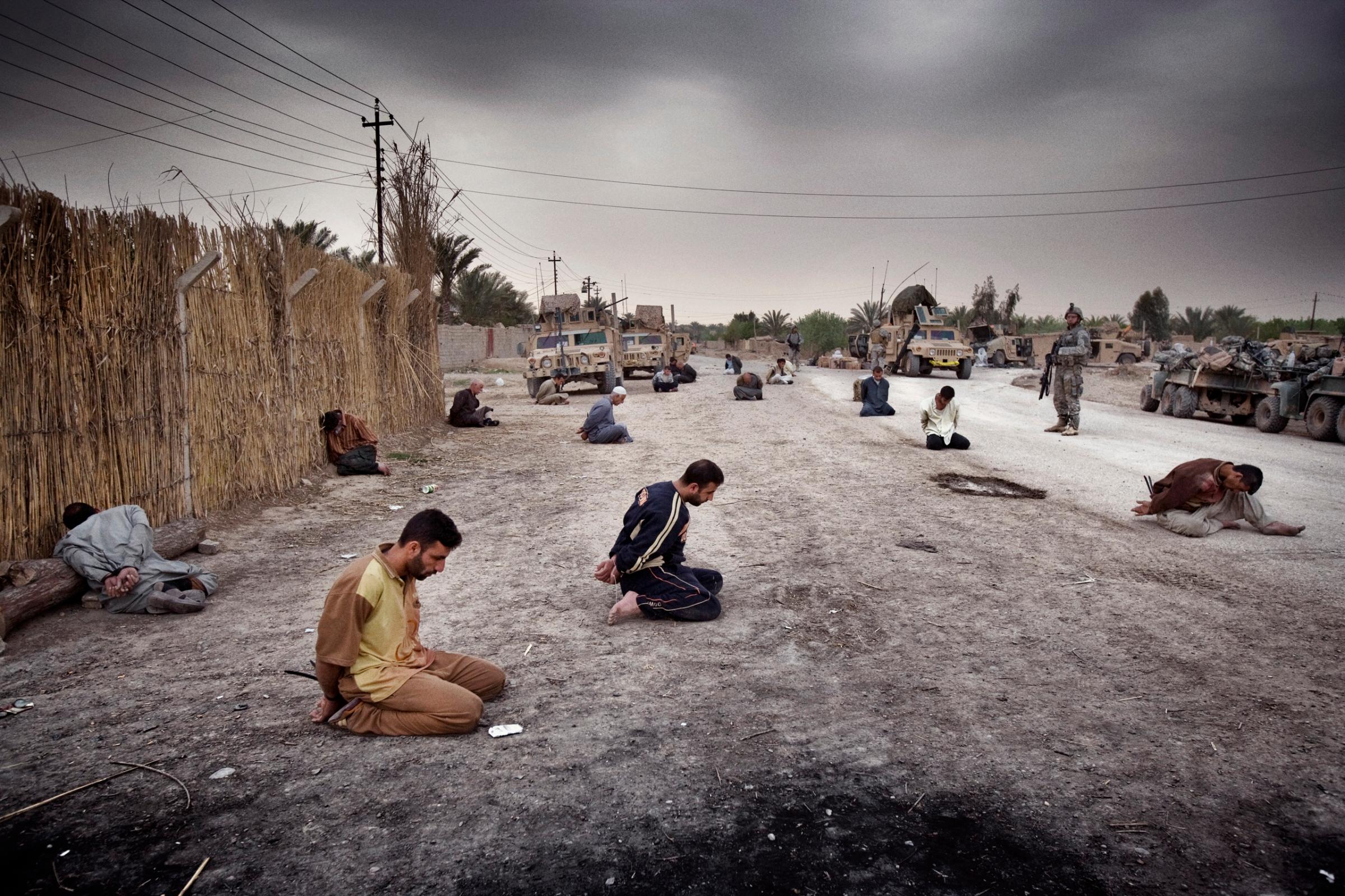 Men arrested by U.S. forces sit bound in the street after a roadside bomb attack in Qubah, Iraq, that left four Americans and one Iraqi boy dead, March 25, 2007.