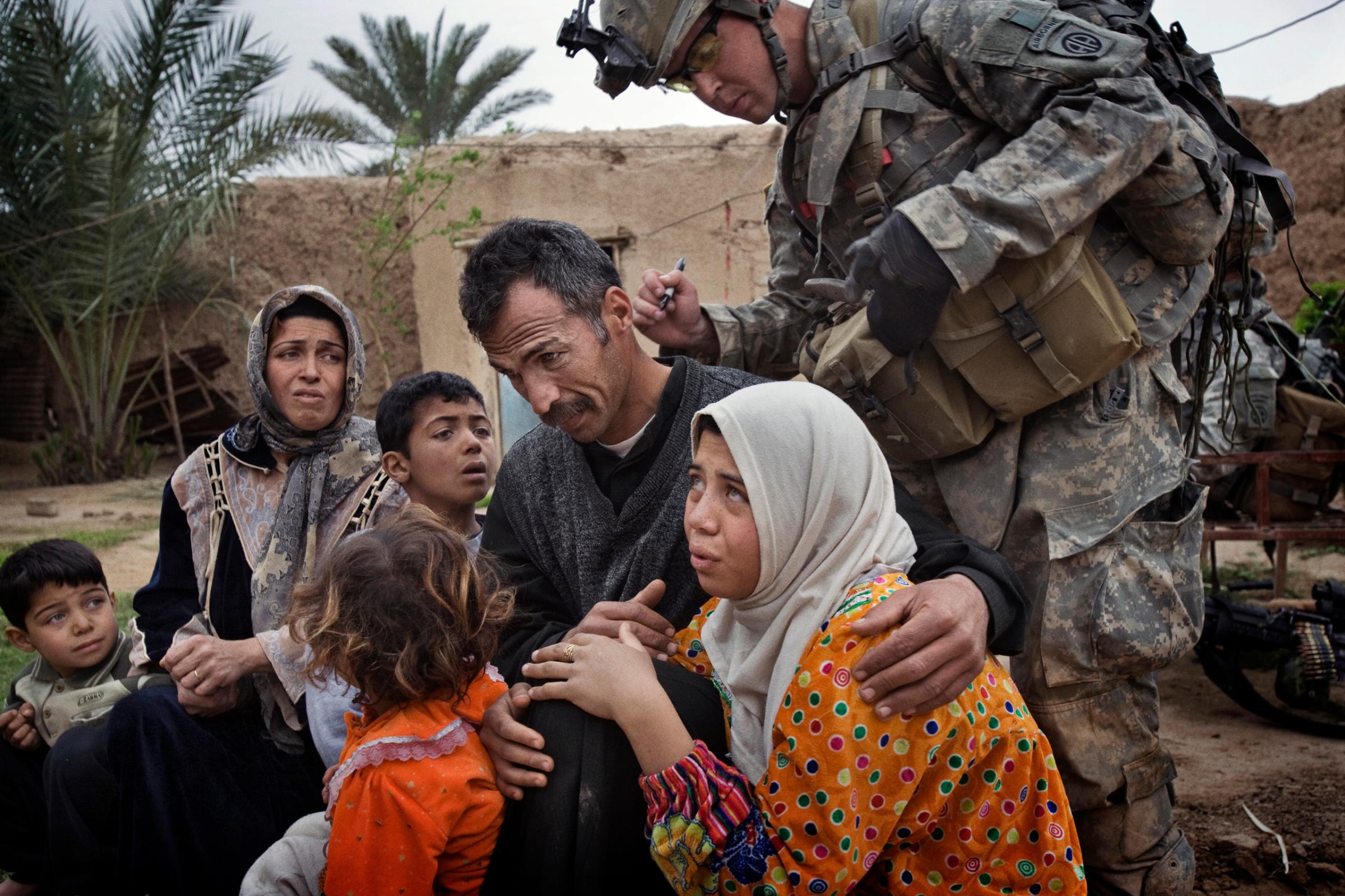 A U.S. soldier marks the neck of a man with identifying numbers. The numbering system allowed U.S. troops to tell whether anyone was moving about the village, despite a lockdown, Qubah, Iraq, March 24, 2007.
