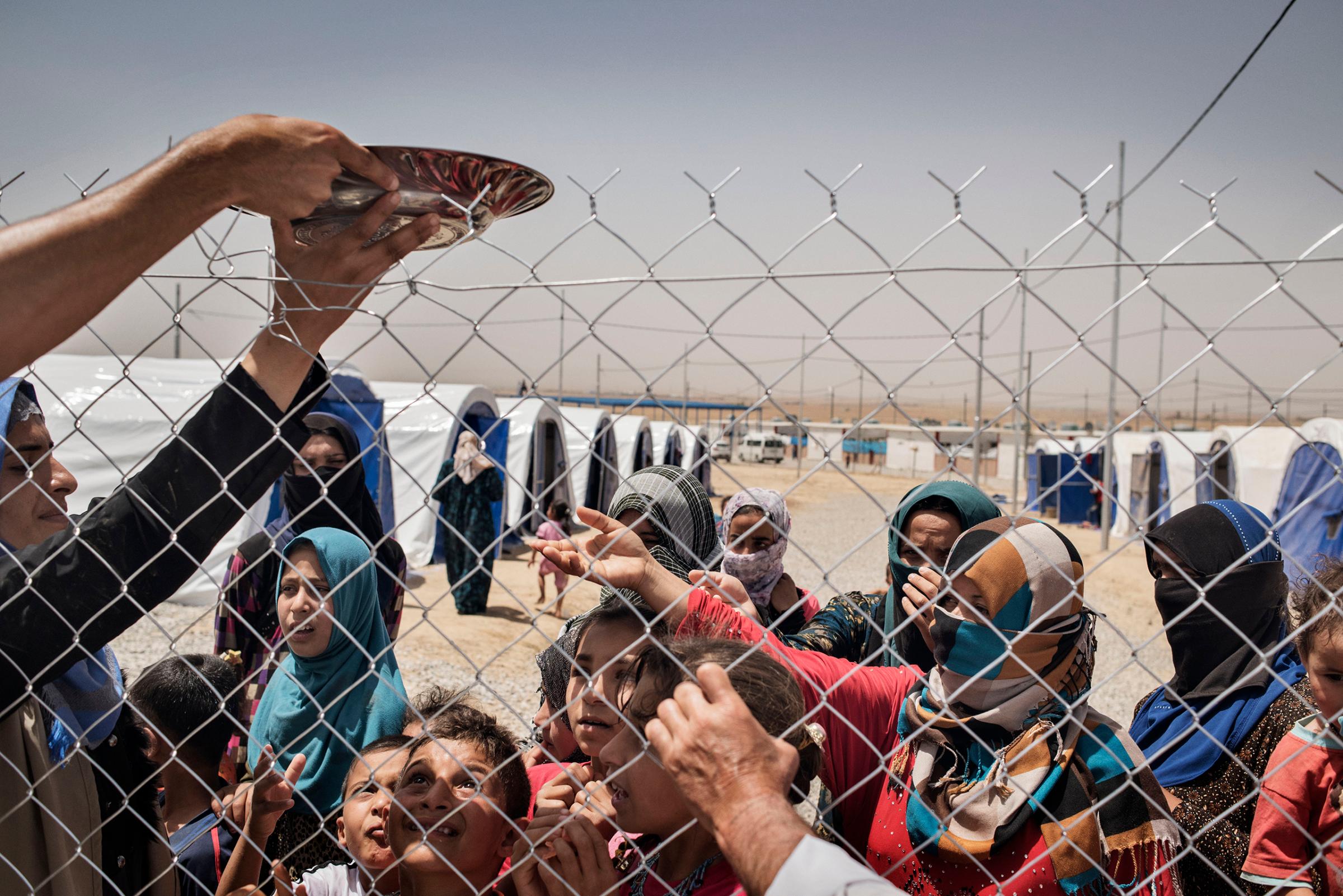 Displaced people stand in front of a fence in a camp near the Iraqi town of Makhmour, in northern Iraq, May 13, 2016. The United Nations said in April that as many as 30,000 people could be forced to flee instability in the Makhmour area, as the Iraqi military pursues an offensive against Islamic State militants in the district.
