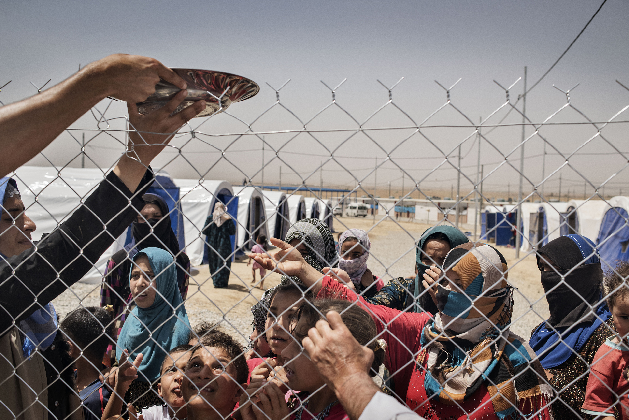 Displaced people stand in front of a fence in a camp near the Iraqi town of Makhmour, in northern Iraq, May 13, 2016. The United Nations said in April that as many as 30,000 people could be forced to flee instability in the Makhmour area, as the Iraqi military pursues an offensive against Islamic State militants in the district. (Yuri Kozyrev—Noor for TIME)