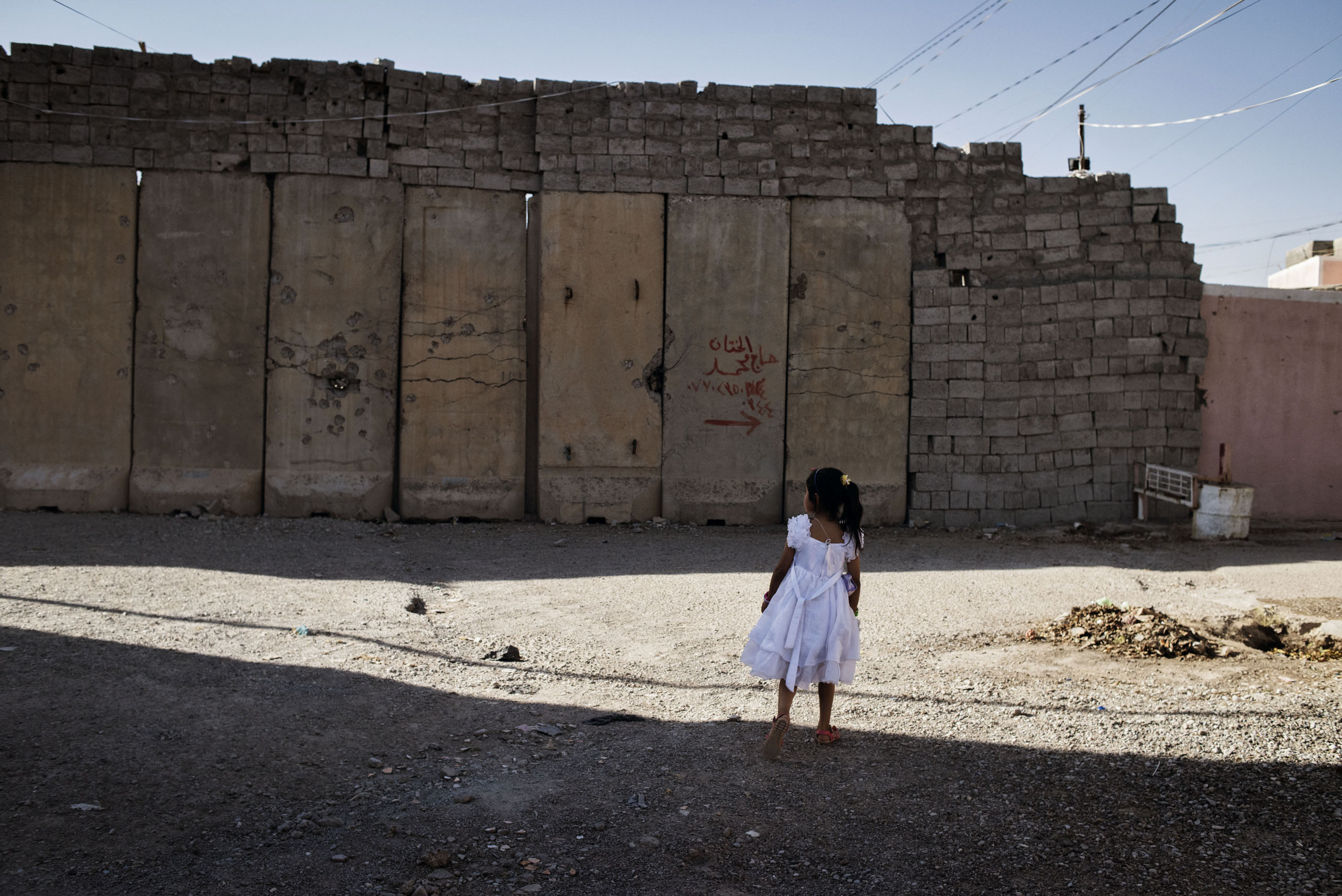 A young girl walks by a wall in the town of Tuz Khurmatu, northern Iraq, May 20, 2016. Walls have been installed in the city as a result of recent fighting between rival Kurdish and Shiite Turkmen factions. The deadly clashes signaled tension among among two groups nominally united in the broader fight against ISIS.
