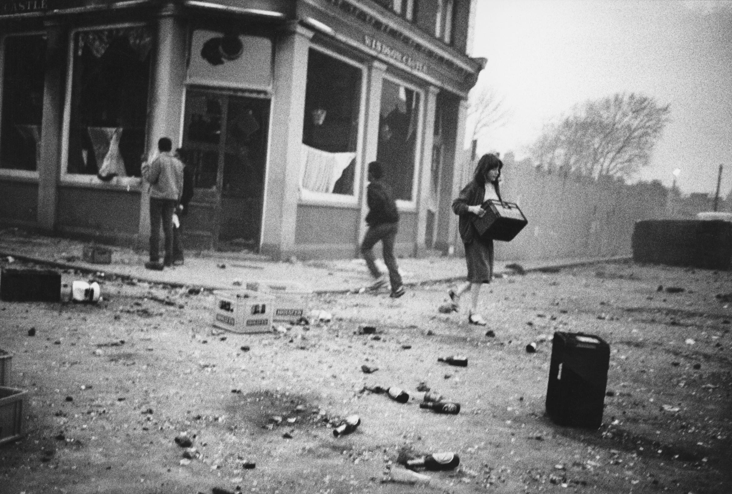 YOUNG LOCALS RELIEVING THE BURNED OUT LOCAL PUB 'THE WINDOW CASTLE' OF ITS CONTENTS ON THE FIRST NIGHT OF THE RIOTS, BRIXTON, APRIL, 1981