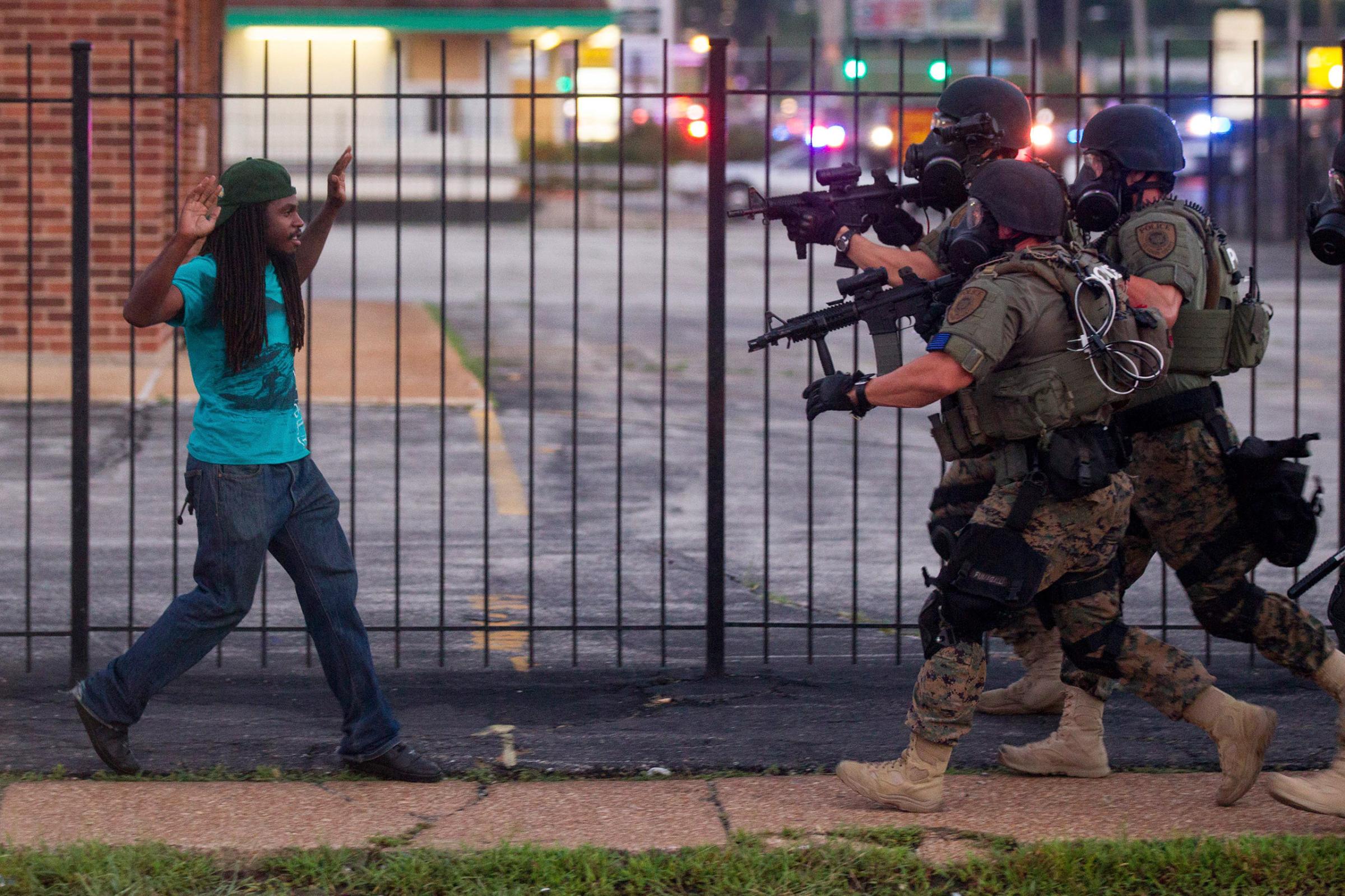 Heavily armed and equipped police confront, and eventually detain, a man during protests two days after the fatal shooting of Michael Brown, in Ferguson.
