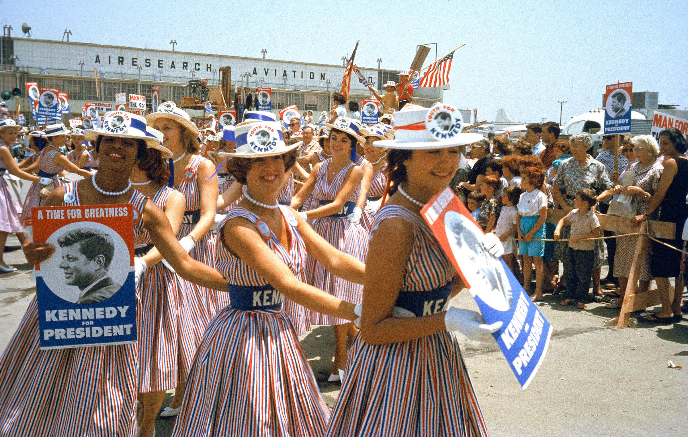 Female supporters of Democratic Presidential candidate John F. Kennedy, called "Kennedy Cuties" form a conga line at the airport while awaiting their candidate's arrival for the Democratic National Convention, 1960.