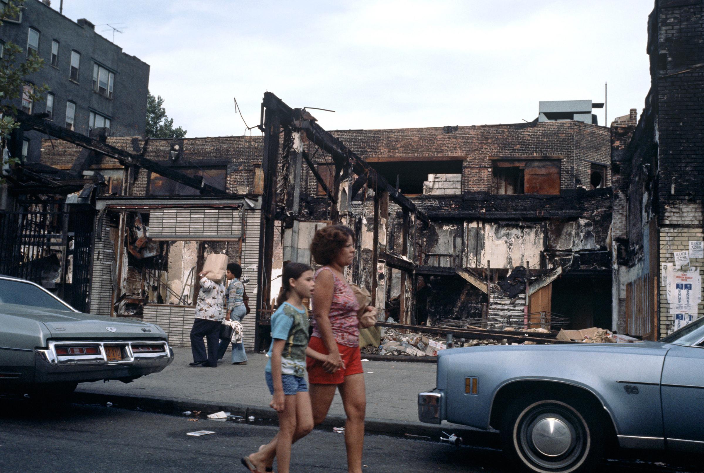 People walking by abandoned burnt-out shops in the South Bronx,1977.