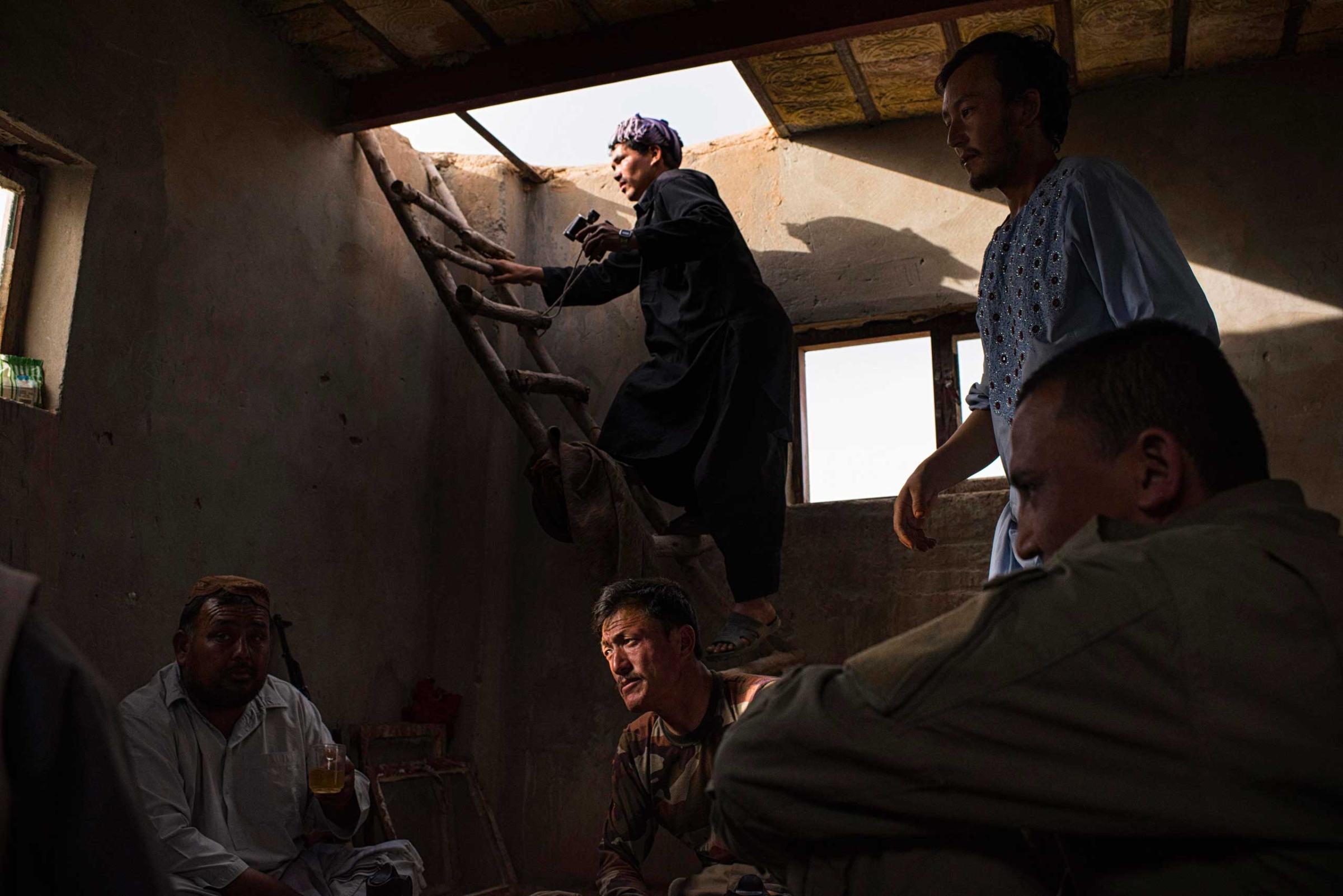 Members of the Afghan Local Police (ALP), one climbing a ladder to keep watch over adjacent fields across which Taliban have conducted raids, inside an ALP outpost in the Sayedabad area of Helmand's Nadali District. Taliban-controlled villages are only a few hundred metres away. After years of relative calm in Nadali District, the ALP, with the support of the Afghan National Army (ANA), are now maintaining the tenuous frontline against the ever-encroaching Taliban who have pushed closer than ever to the nearby Provincial capital, Lashkar Gah, in recent months. The ALP are between a rock and a hard place - unable to lay down their arms because of the immediate proximity of Taliban fighters but under-equipped to provide adequate protection for the villages they protect and call home.