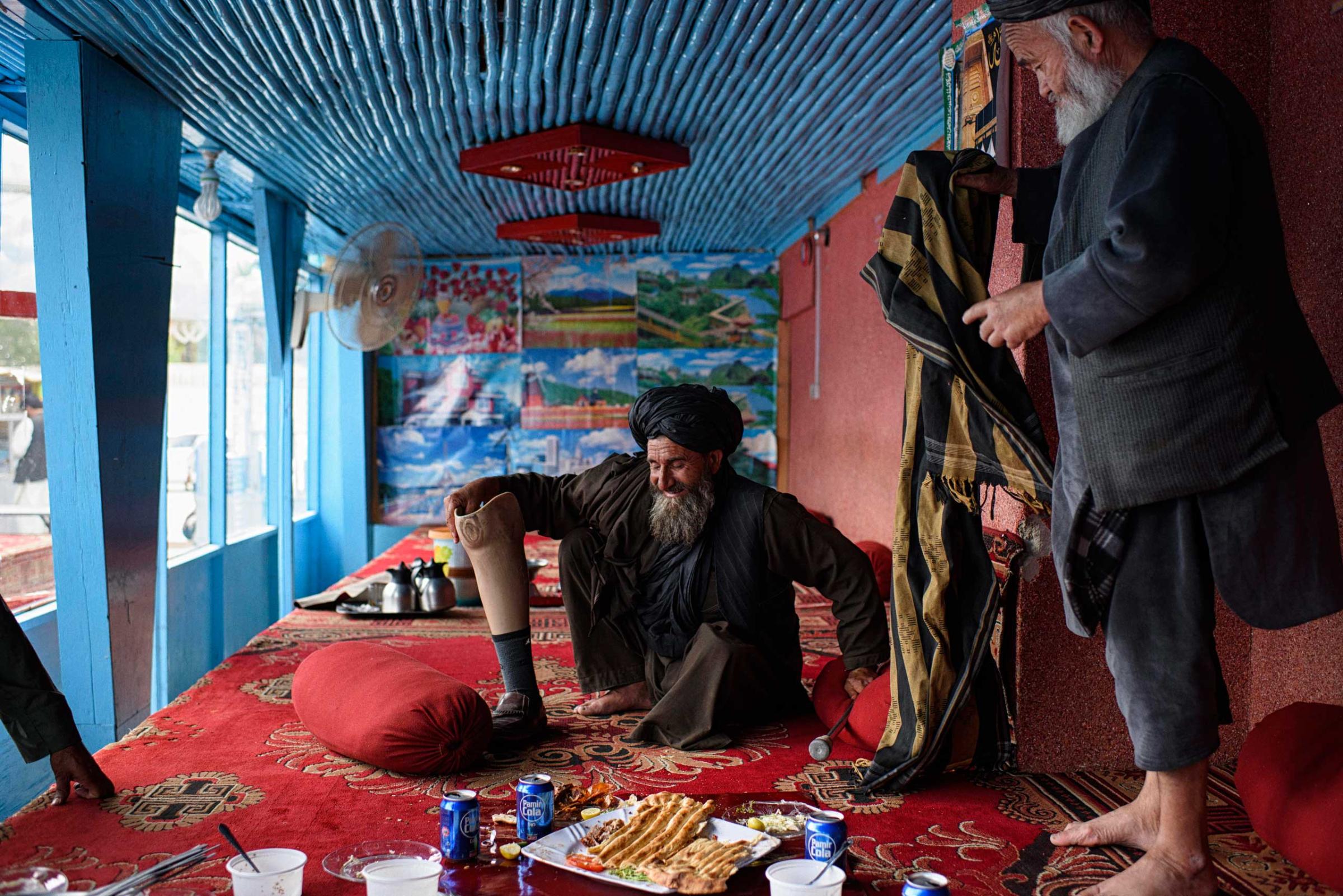 After lunch at a popular restaurant in Lashkar Gah, a guest fits his prosthetic leg before departing with friends.