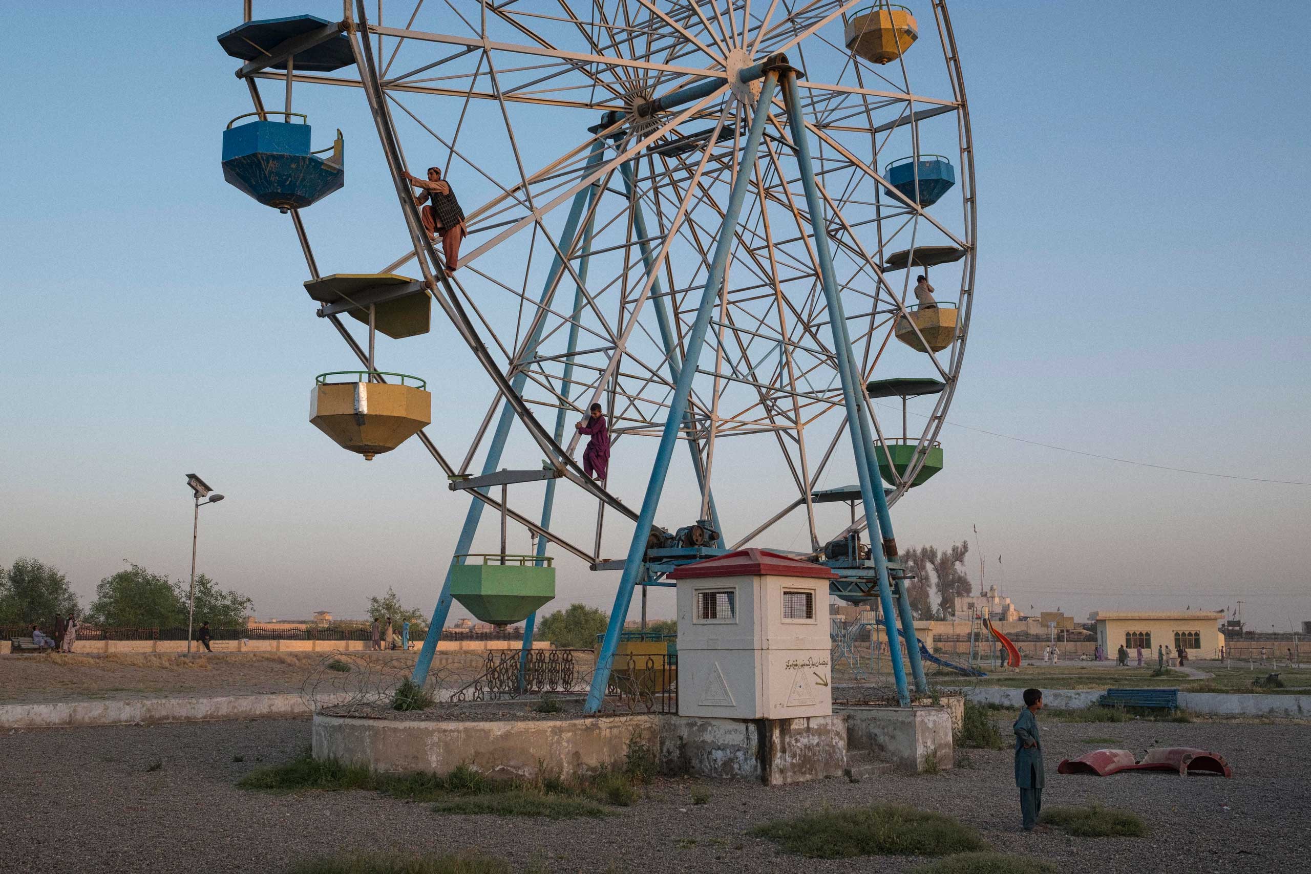Young boys climb a broken-down Ferris Wheel in order to give a friend a quarter of a revolution ride, in a dilapidated playground in the capital of Helmand Province, Lashkar Gah.