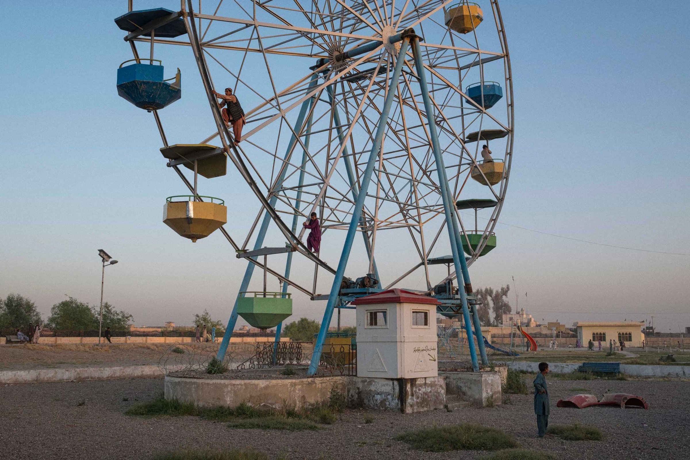Young boys climb a broken-down Ferris Wheel in order to give a friend a quarter of a revolution ride, in a dilapidated playground in the capital of Helmand Province, Lashkar Gah.