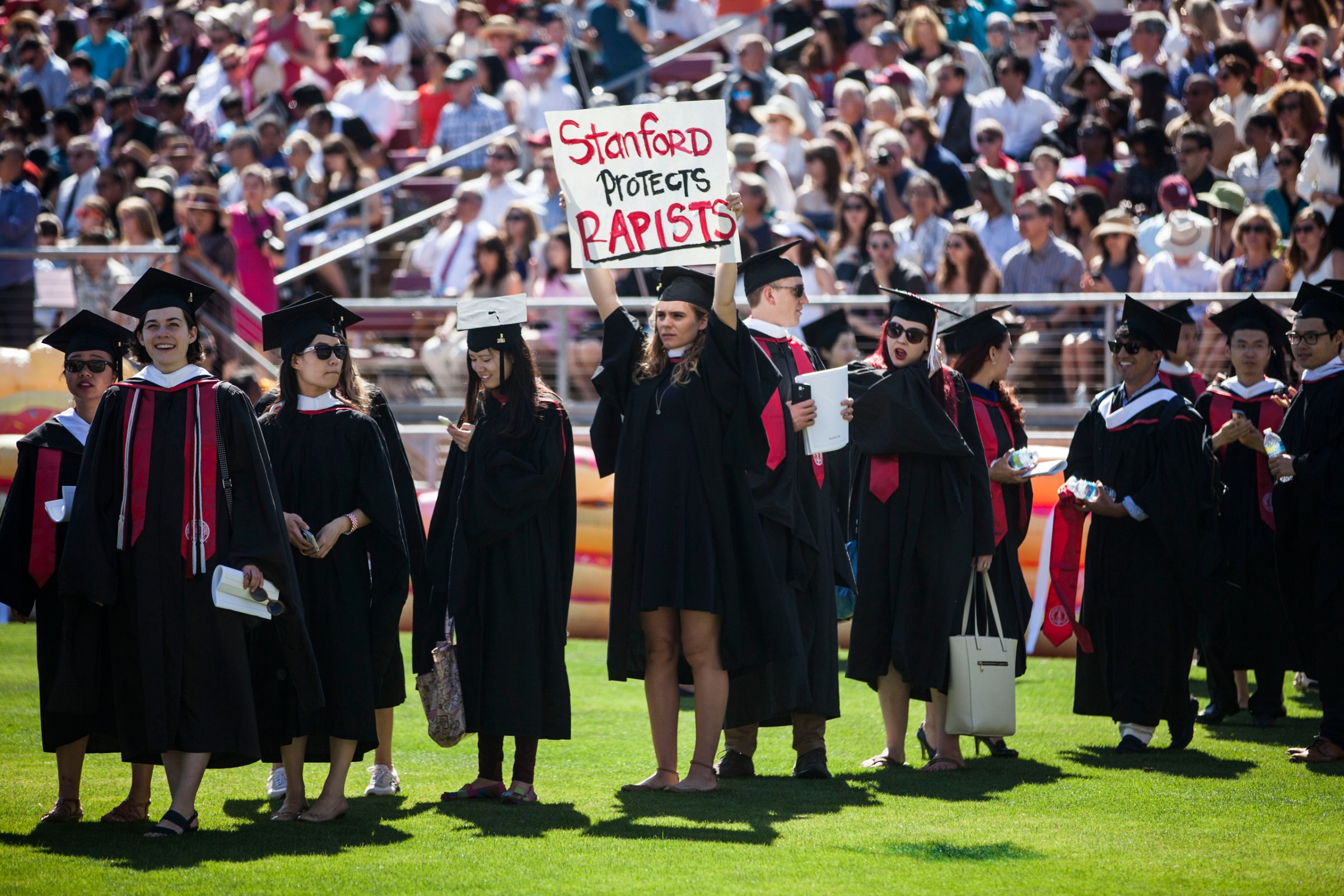 Graduating student, Andrea Lorei, who help organize campus demonstrations holds a sign in protest during the 'Wacky Walk' before the 125th Stanford University commencement ceremony in Stanford, Calif. on June 12, 2016.