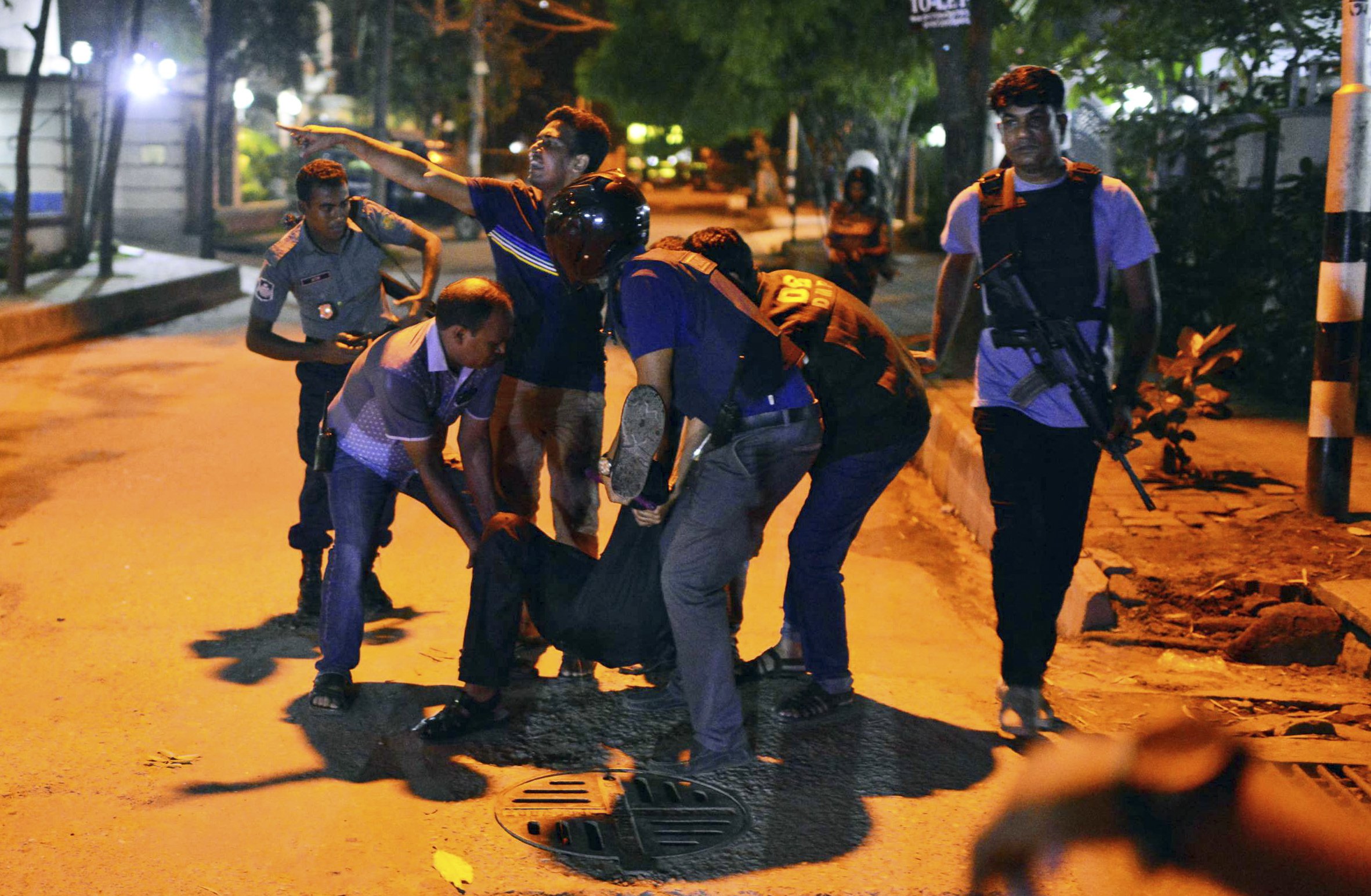 People help an unidentified injured person after a group of gunmen attacked a restaurant popular with foreigners in a diplomatic zone of the Bangladeshi capital of Dhaka on July 1, 2016. (AP)