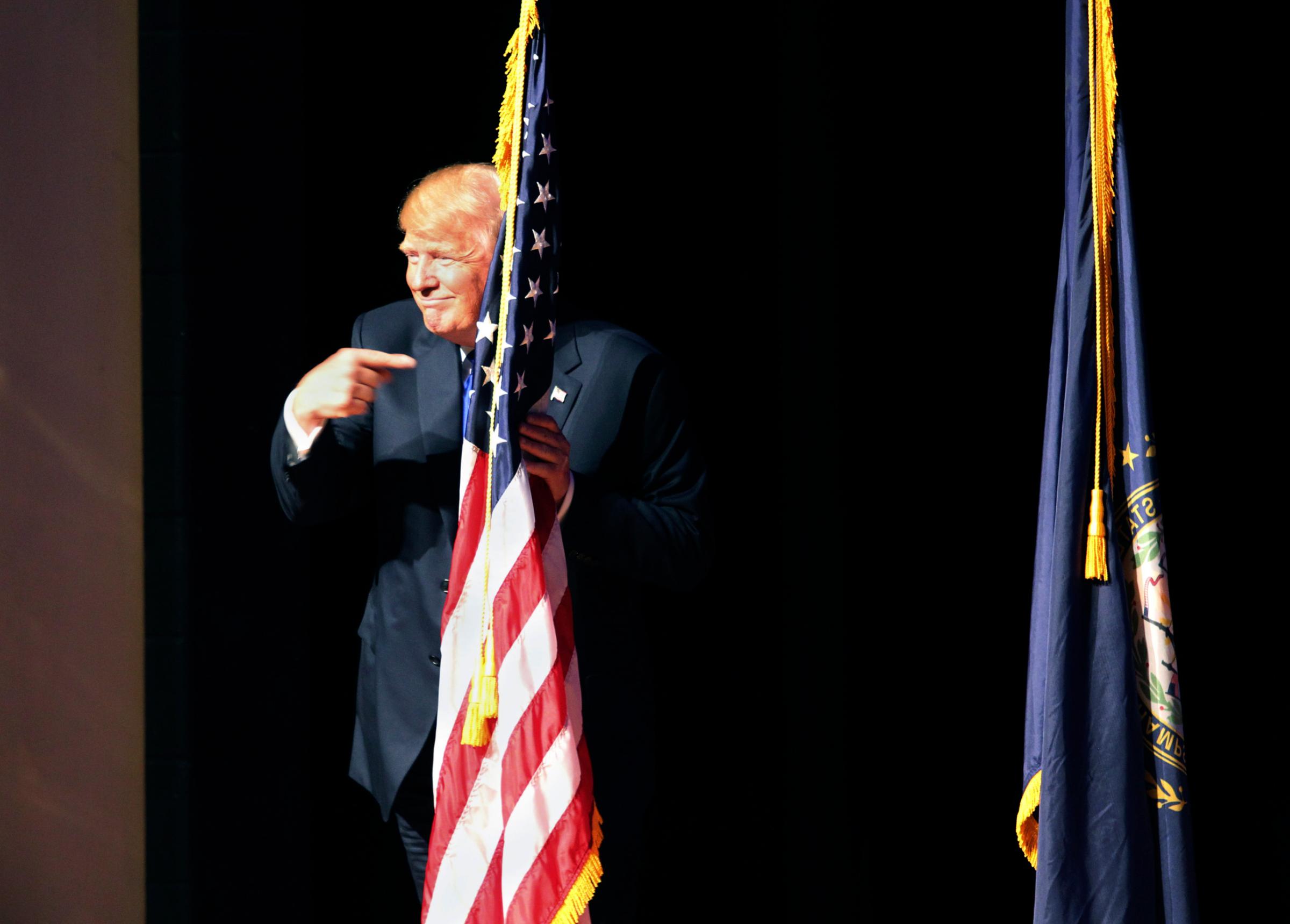 Republican presidential candidate Donald Trump points to the American flag as he takes the stage to speak to a campaign town hall at Pinkerton Academy in Derry, N.H. on Aug. 19, 2015.