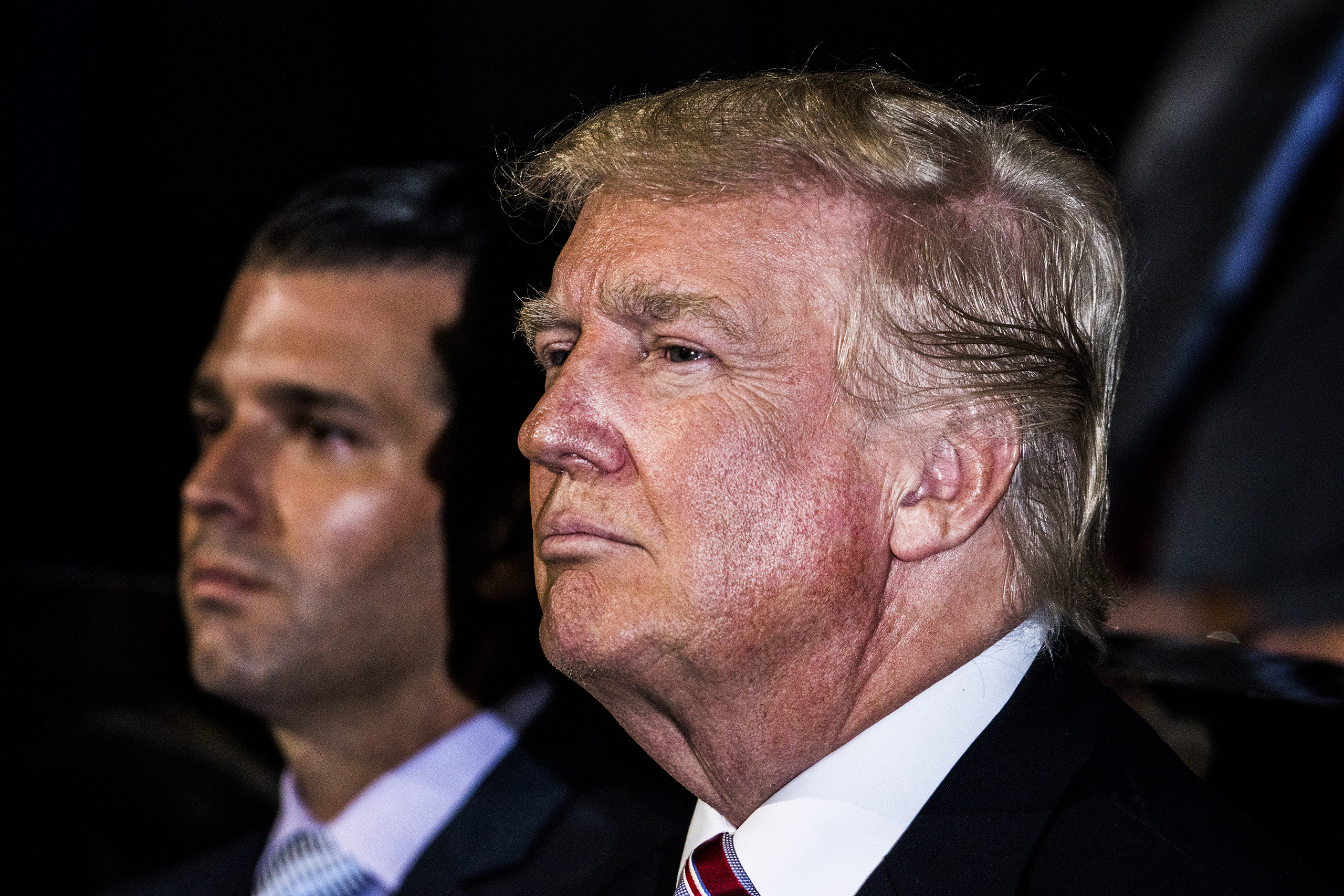 Republican presidential candidate Donald Trump and Donald Trump Jr listen to Eric Trump on July 20, 2016, at the Quicken Loans Arena in Cleveland, Ohio.