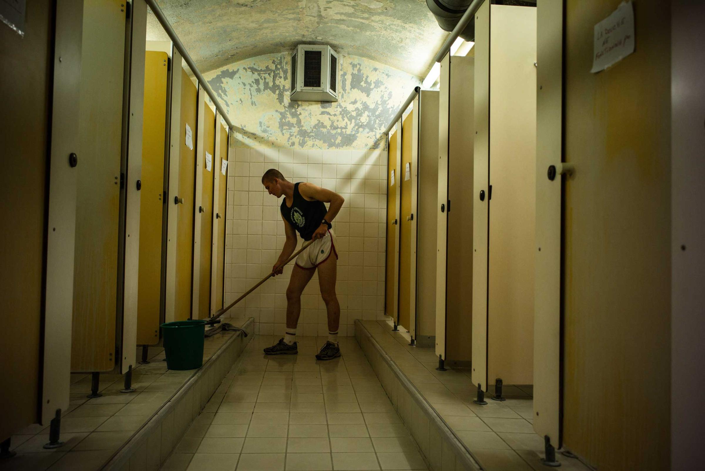 A member of the French Foreign Legion, disciplined by his superiors, cleans the toilets of the Training camp's compound. Aug. 6, 2015.