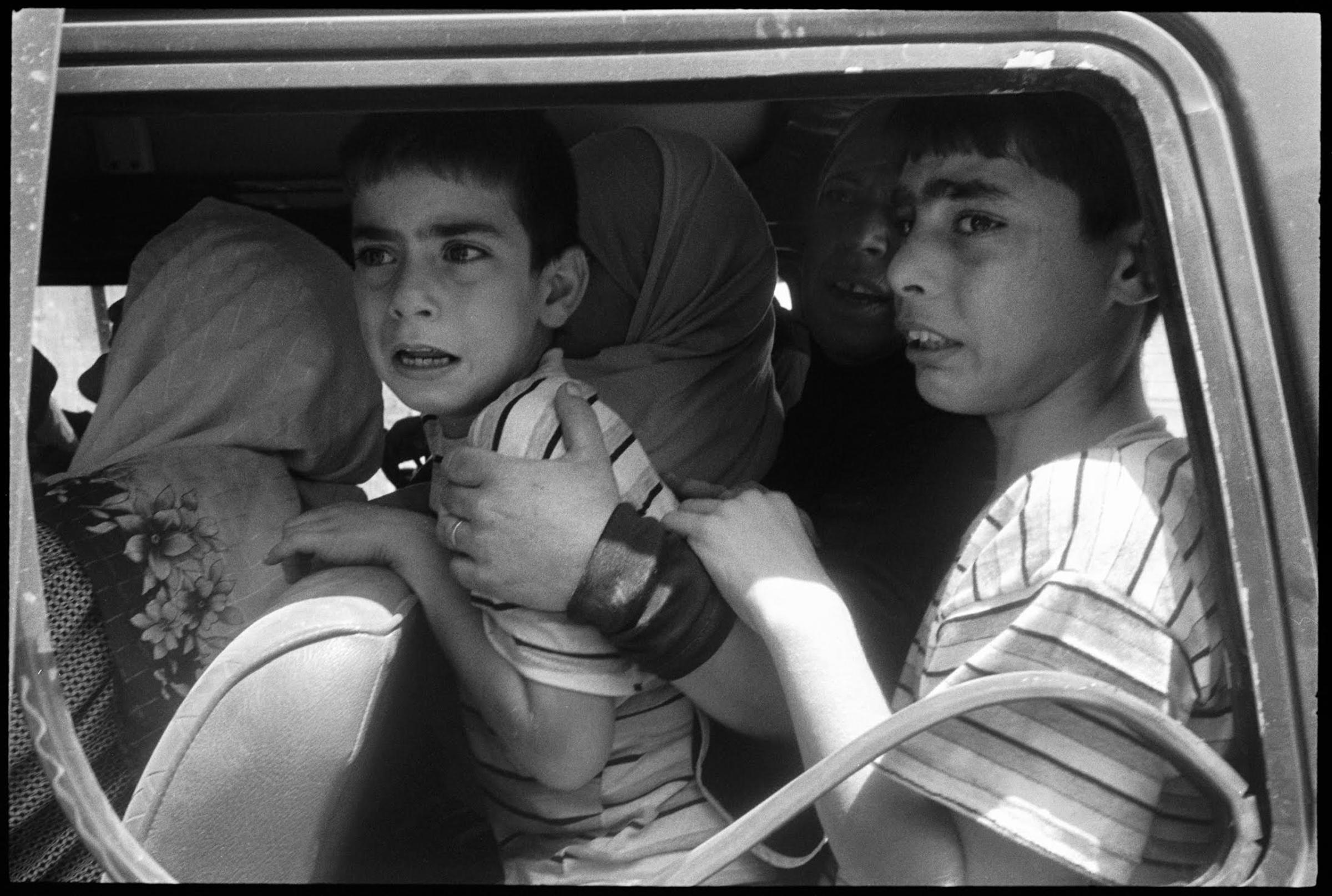 I'm a mother of two young boys now. I understand this photograph in a way that I wasn't capable of when I took it. We all took advantage of a temporary halt in Israeli air strikes in the middle of the war. Journalists were finally safer to drive around, and those trapped in bombarded villages were given an opportunity to escape. We entered Aitaroun and found people emerging out of a flattened village. It was a moment of chaos as people realized it was quiet and safe to flee. At the time, there were only enough vehicles to evacuate women and children. It was a moment of true fear, as these boys knew they were leaving their father behind.