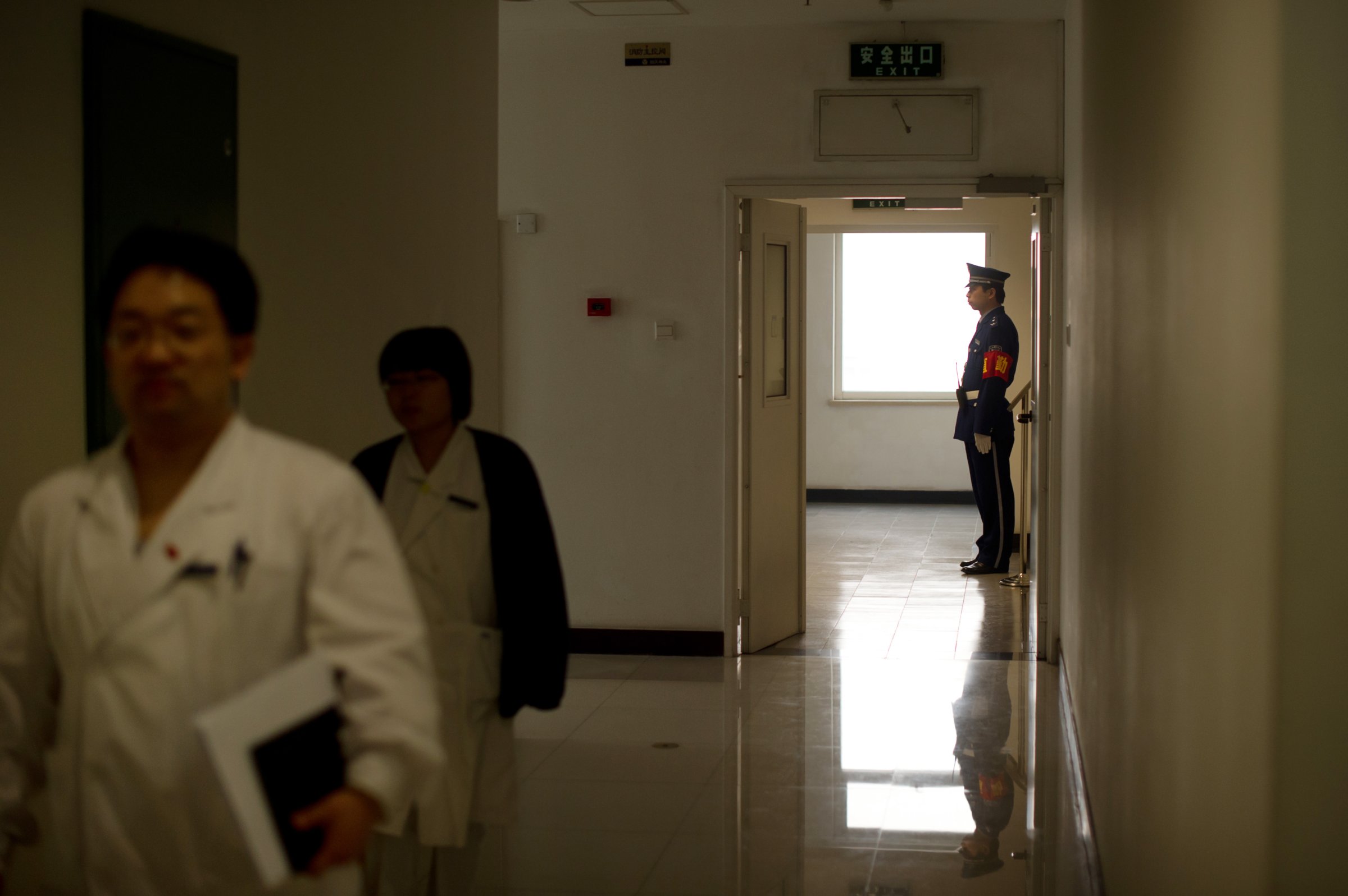 Hospital staff walk past a security guar