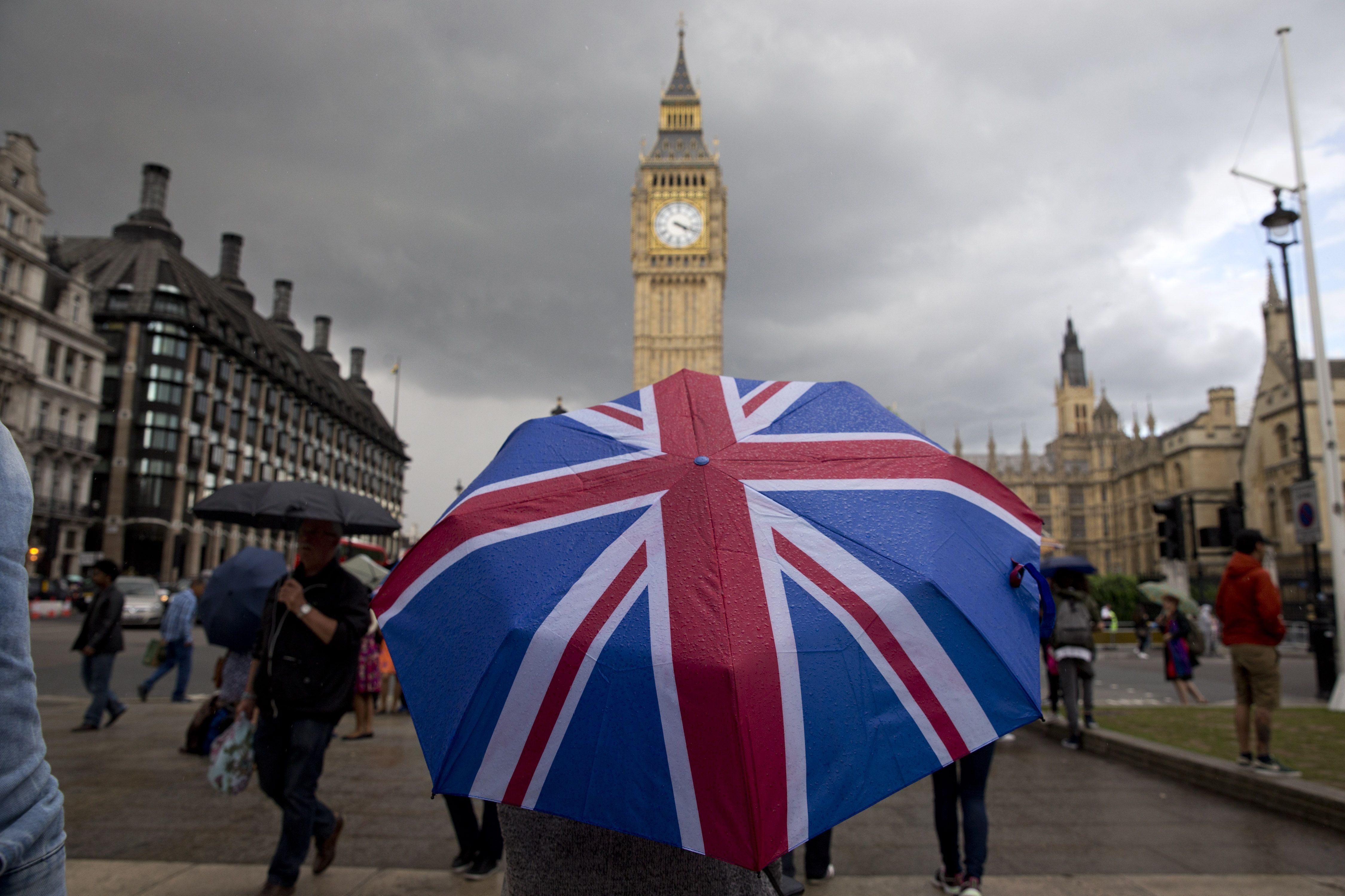 A pedestrian shelters from the rain beneath a Union flag themed umbrella as they walk near the Big Ben clock face and the Elizabeth Tower at the Houses of Parliament in central London on June 25, 2016 (Justin Tallis—AFP/Getty Images)
