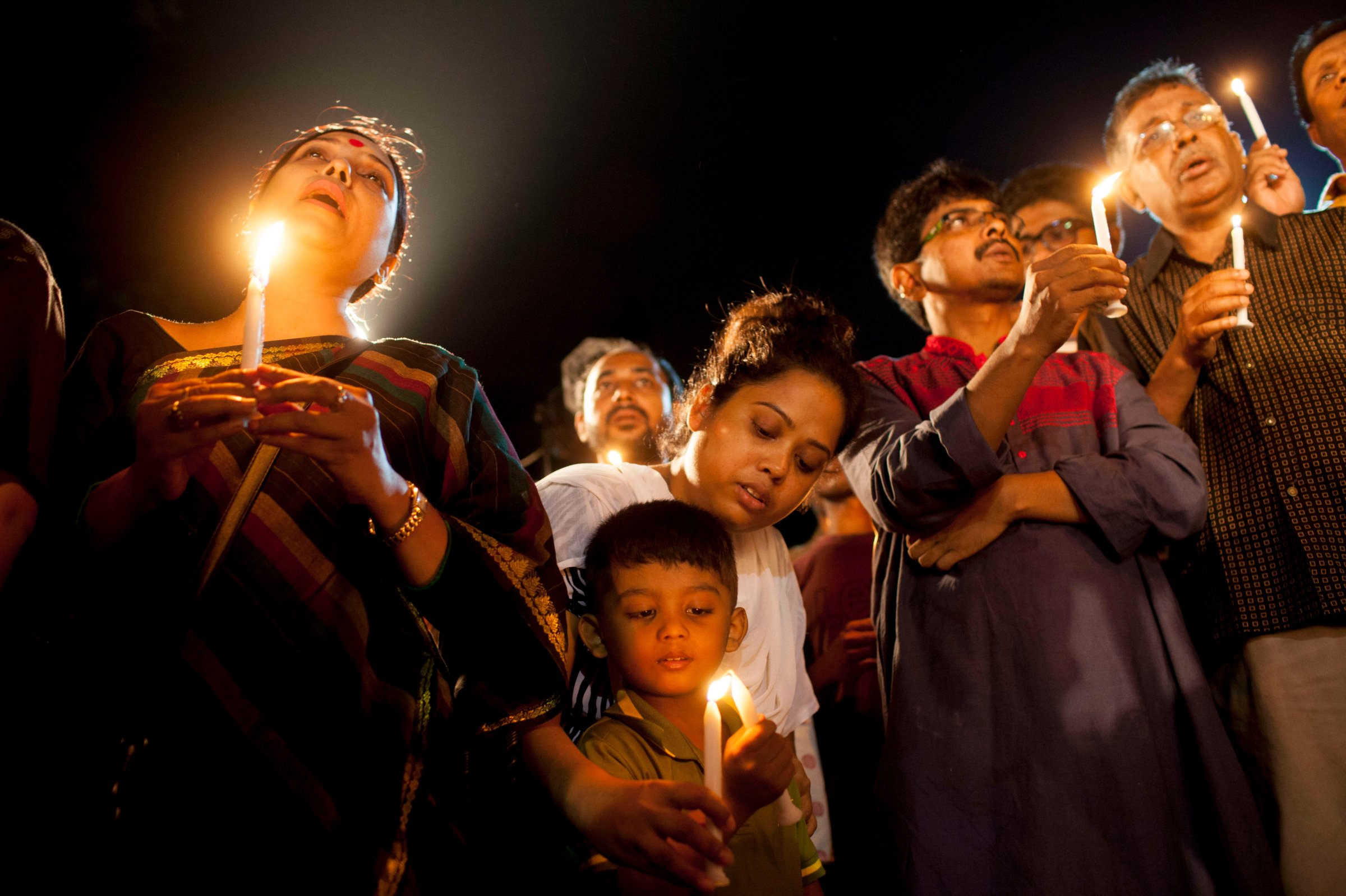 A boy with his family attends a candle-light ceremony to pay