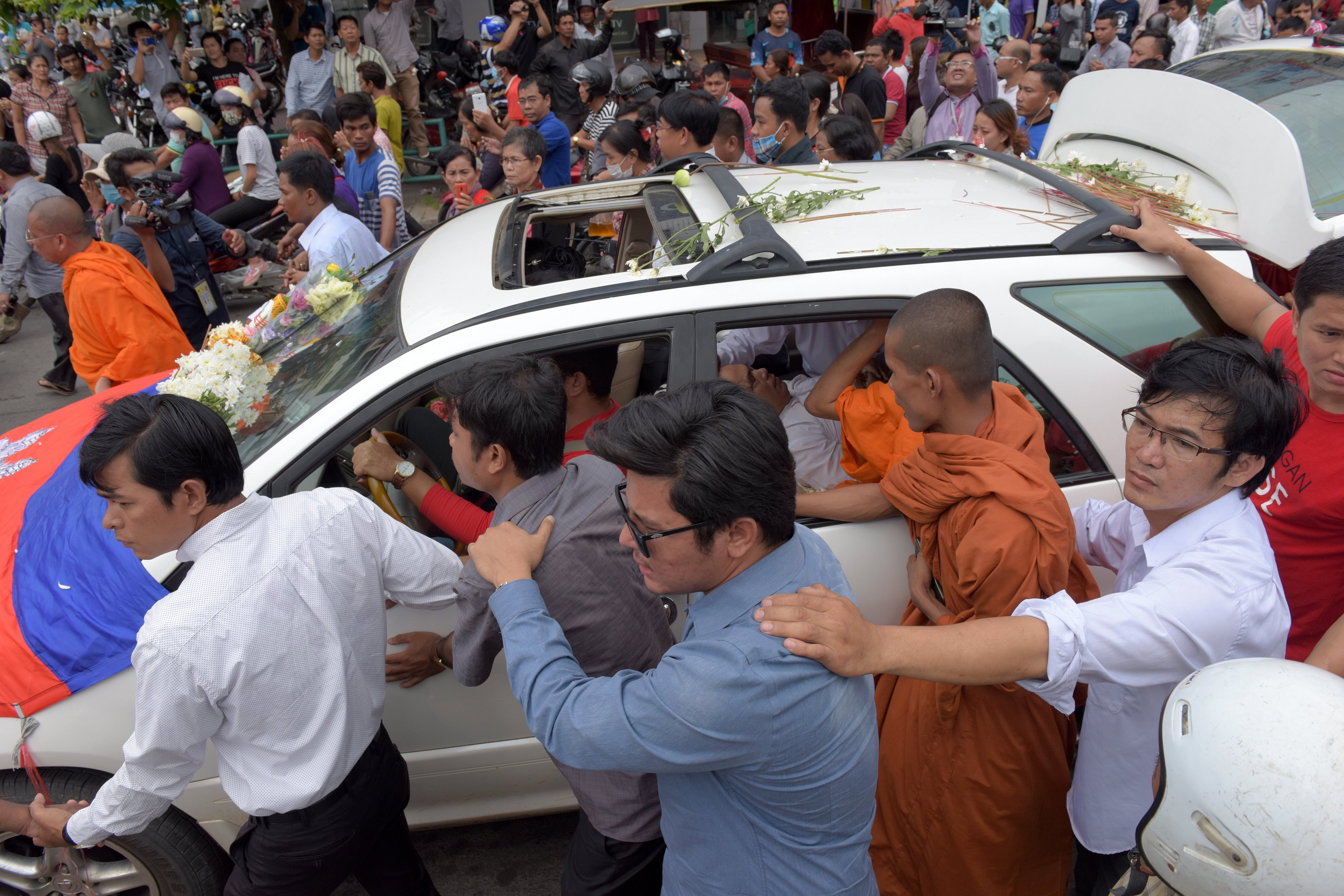 Cambodians walk along a car transporting the body of activist Kem Ley who was shot dead earlier in the day in Phnom Penh on July 10, 2016 (Tang Chhin Sothy—AFP/Getty Images)