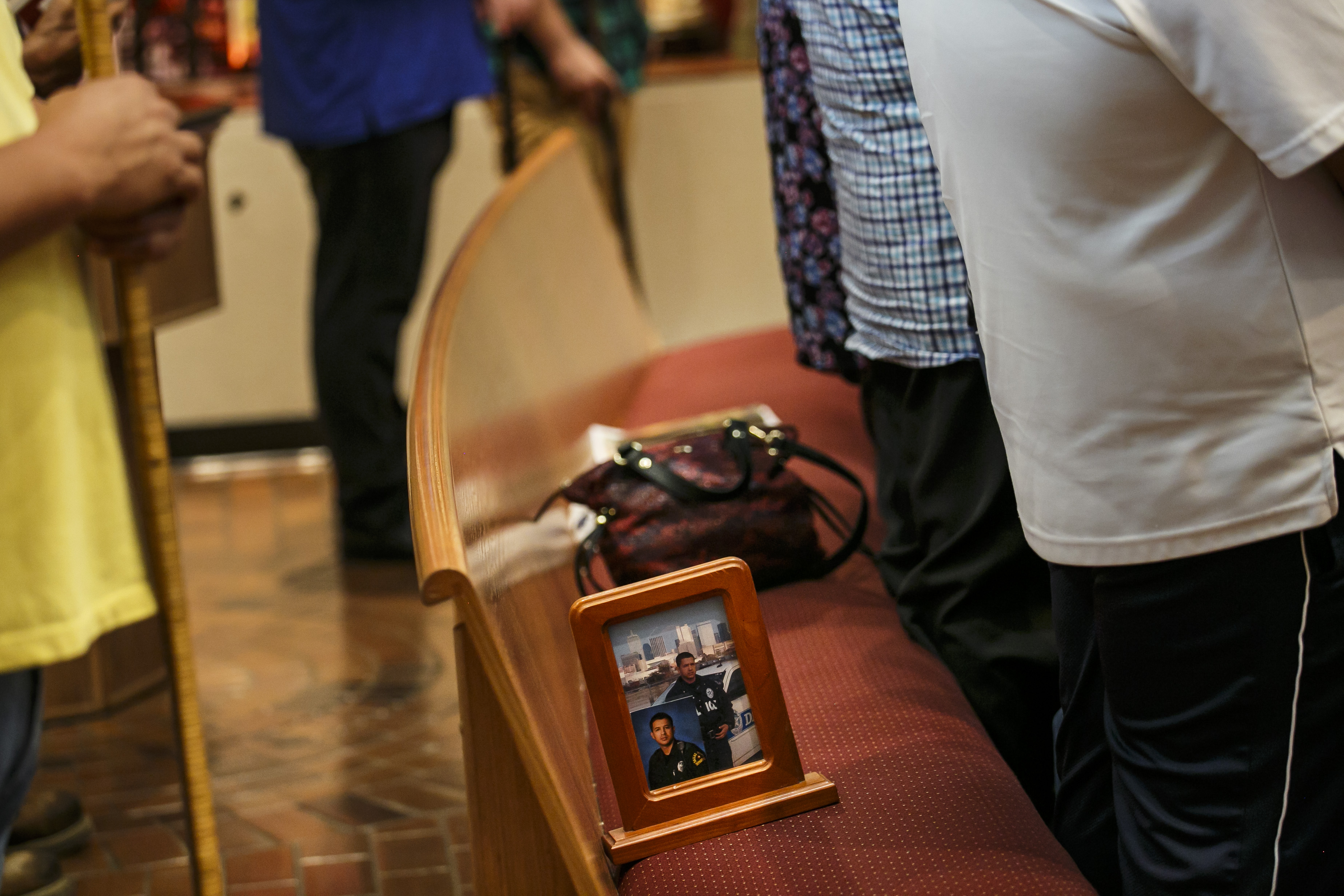 A picture frame with two portraits of slain police officer Patrick Zamarripa, sits on the pew as family members stand to pray during Sunday mass at All Saints Catholic Church, in Dallas, Texas, on July 10, 2016. (Marcus Yam&mdash;LA Times via Getty Images)