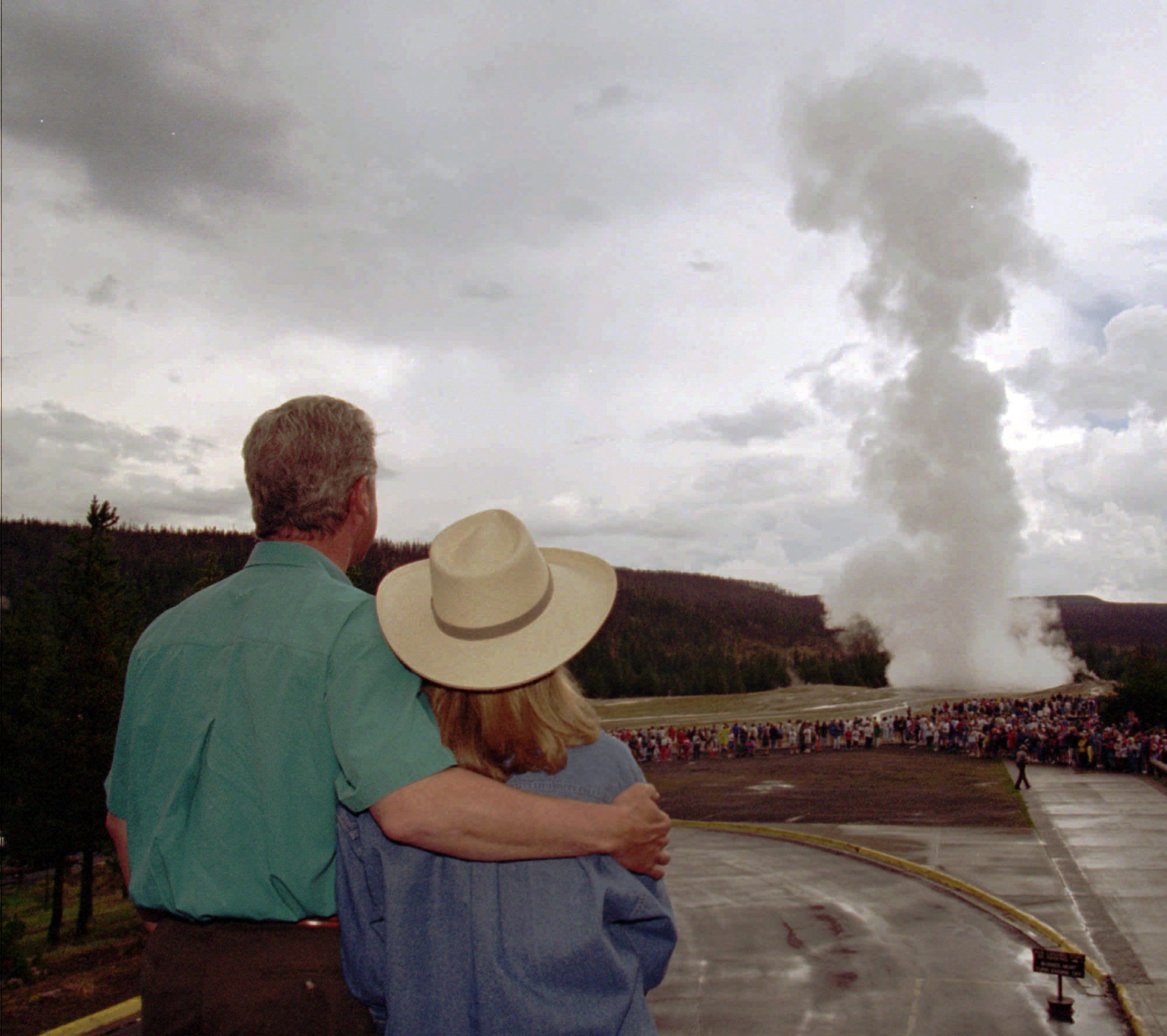 President Bill Clinton puts an arm around his wife, Hillary Clinton, while watching Old Faithful erupt at Yellowstone National Park, Wyo., on Aug. 25, 1995. The first family visited several Yellowstone sites while on vacation.