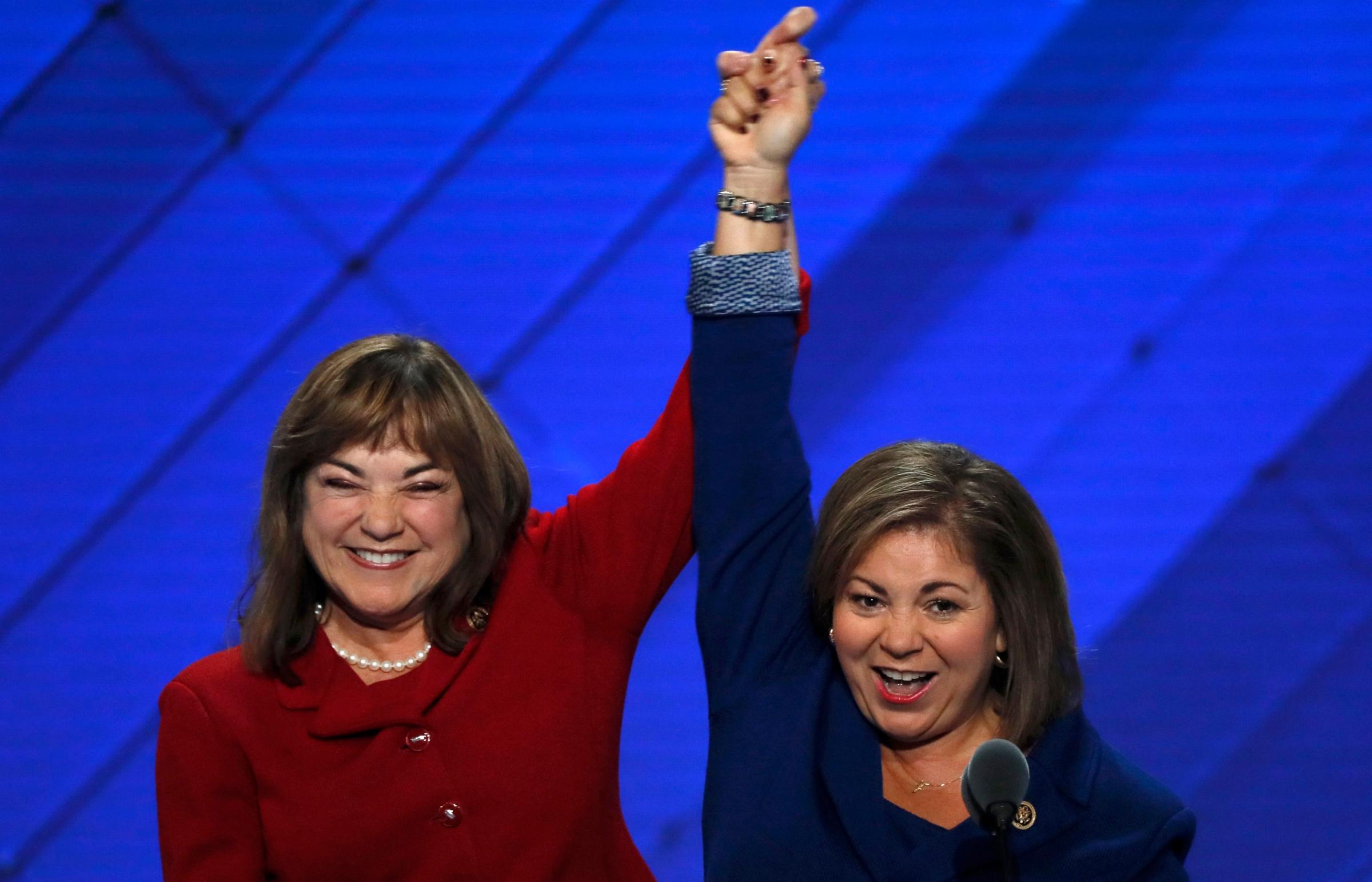 U.S. Rep. Linda Sanchez (D-CA) (R) and her sister and fellow Rep. Loretta join hands onstage at the Democratic National Convention in Philadelphia on July 25, 2016.