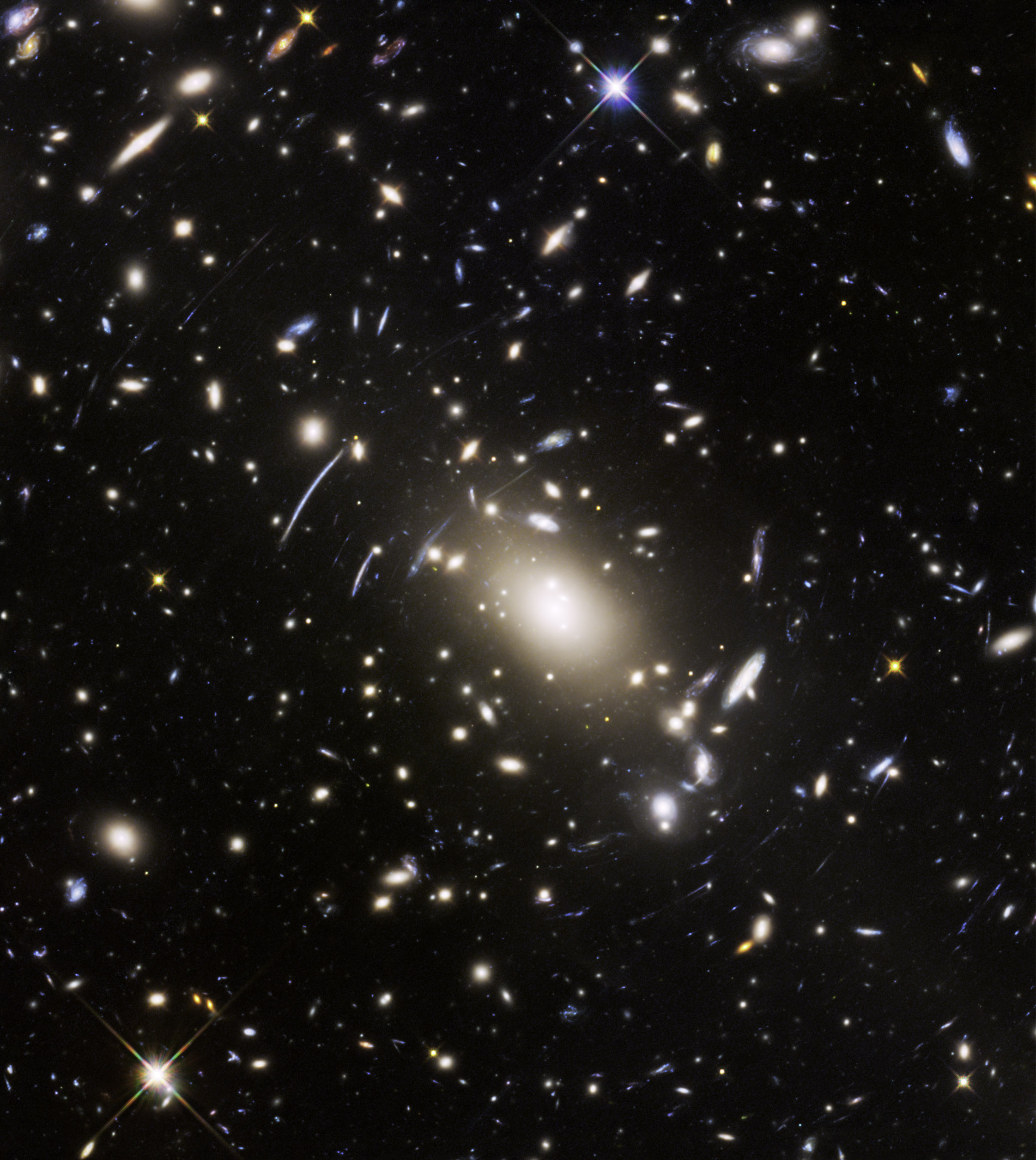 Abell S1063, a galaxy cluster, was observed by the NASA/ESA Hubble Space Telescope as part of the Frontier Fields program. The huge mass of the cluster acts as a cosmic magnifying glass and enlarges even more distant galaxies, so they become bright enough for Hubble to see. (NASA, ESA, and J. Lotz (STScI))