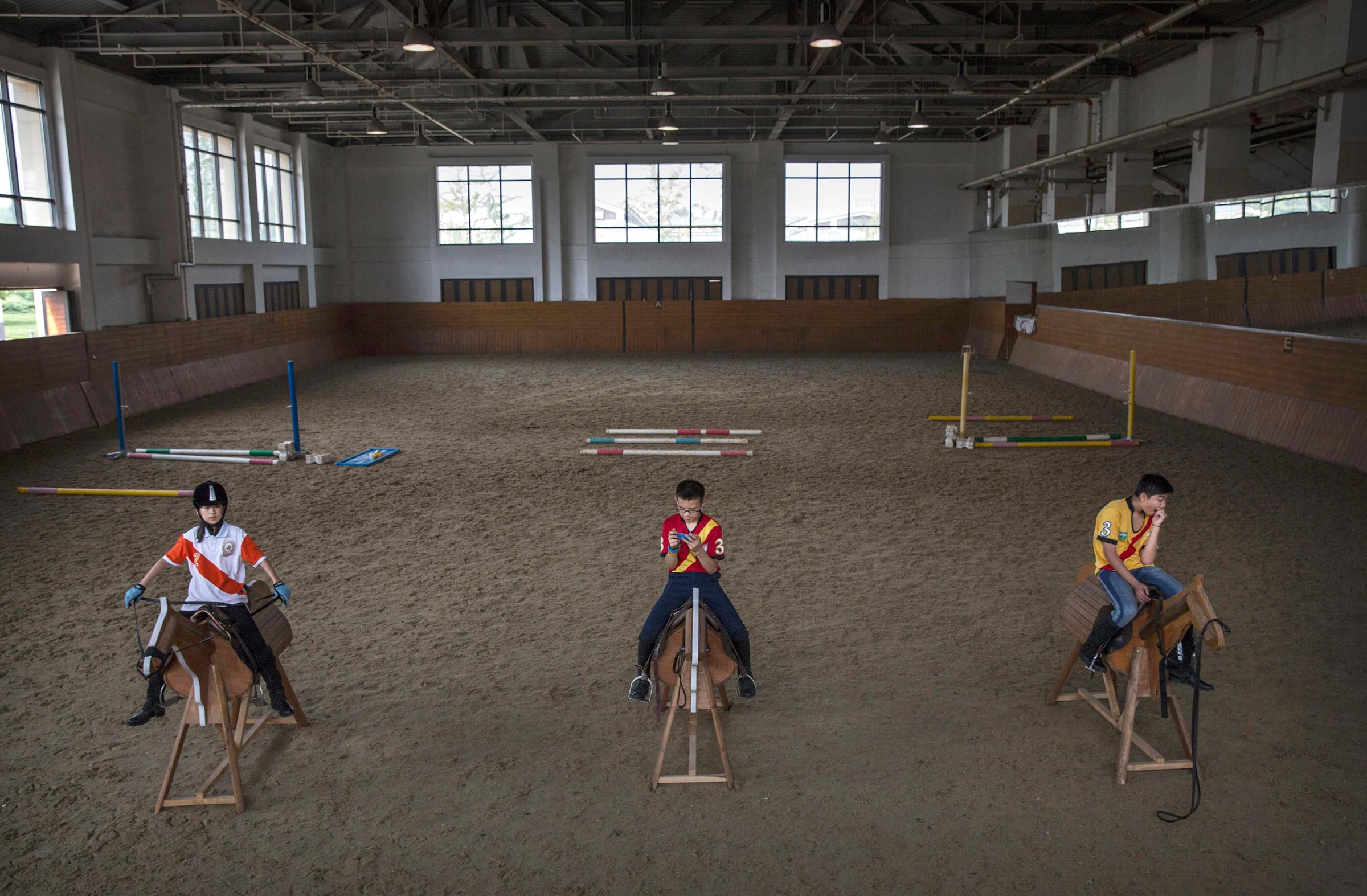 Young Chinese players from the Junior Polo Program sit on wooden horses at a summer training camp held at the Tianjin Goldin Metropolitan Polo Club in Tianjin, China, on July 16, 2016.