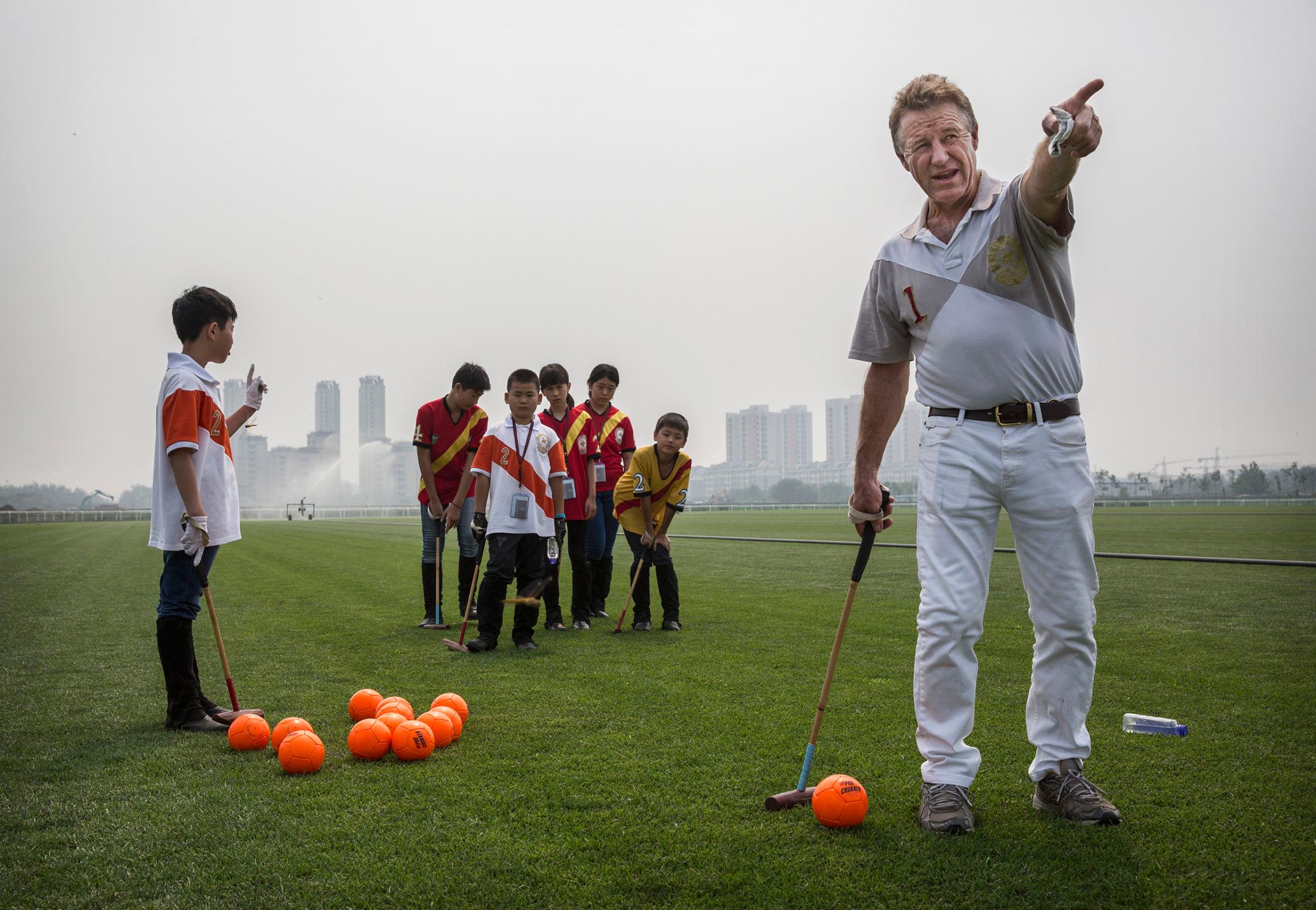 Derek Reid, director of Polo Operations, gestures as he instructs young Chinese players from the Junior Polo Program during stick and ball training at a summer camp held at the Tianjin Goldin Metropolitan Polo Club in Tianjin, China, on July 17, 2016.