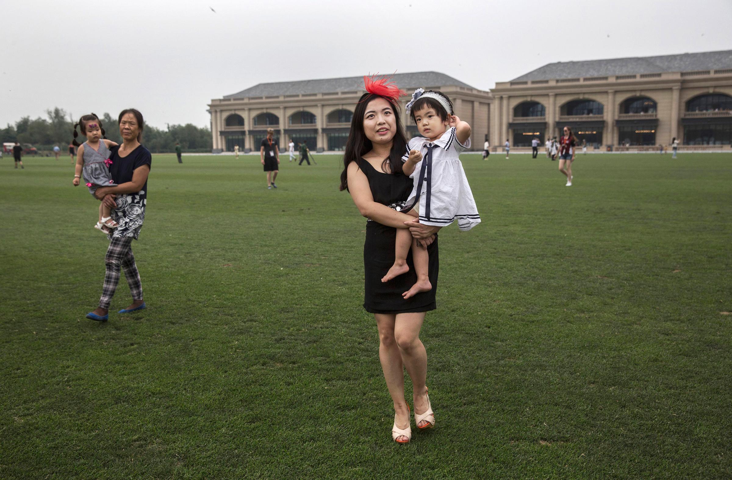 A woman walks across the field with her children during a break in an intervarsity match at the Tianjin Goldin Metropolitan Polo Club in Tianjin, China, on July 16, 2016.