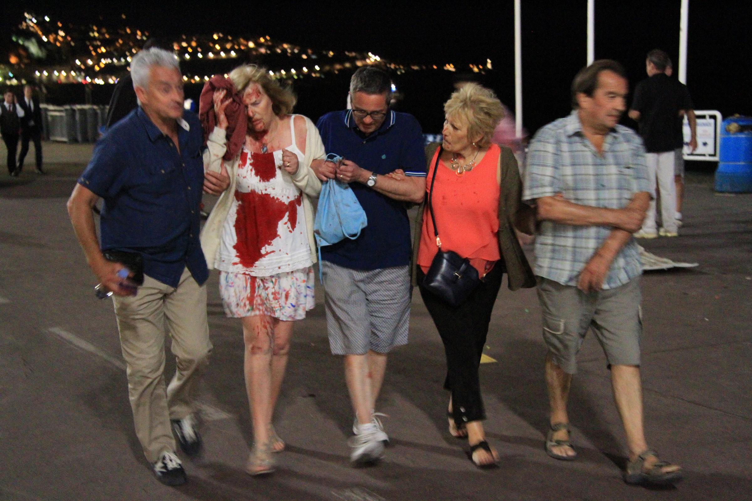 A woman whose shirt is covered in blood is helped after authorities said a truck slammed into a crowd in Nice, France, on July 14, 2016. French officials said more than 70 people were killed.