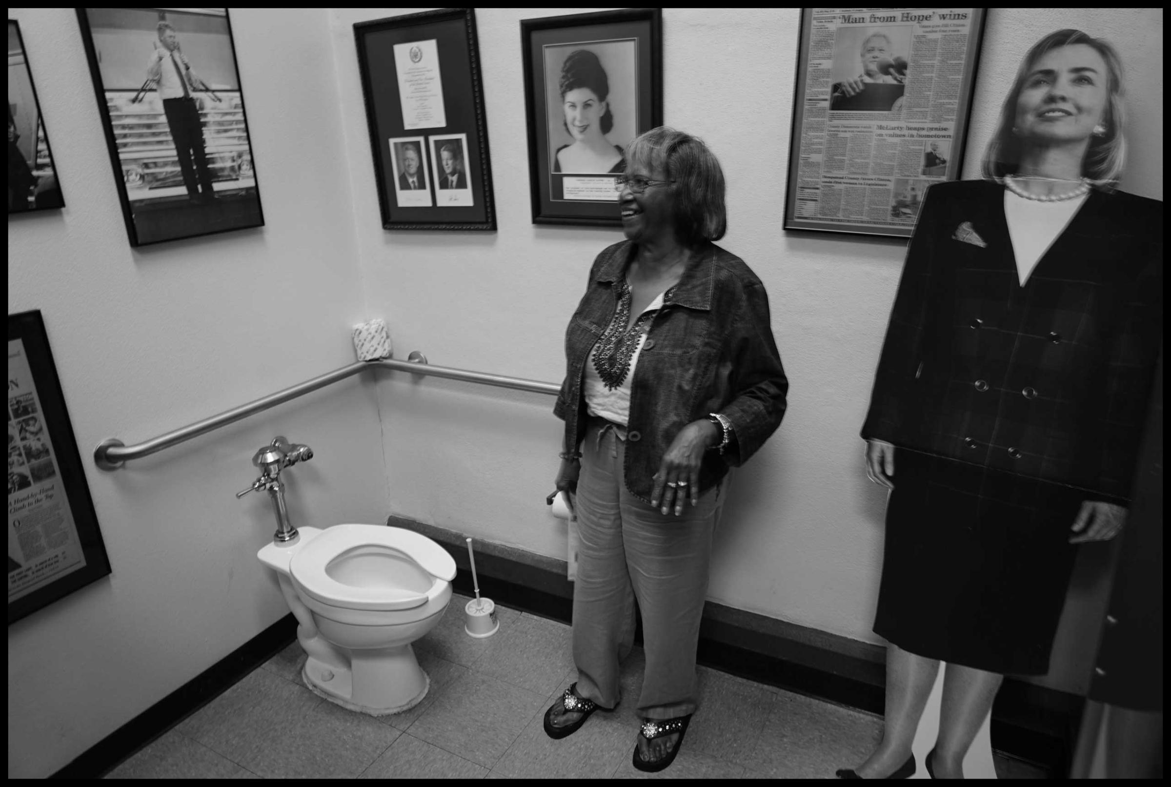 Margaret Smith inside female rest room where placard of Hillary Clinton is on display. Hope, AR. 2016.