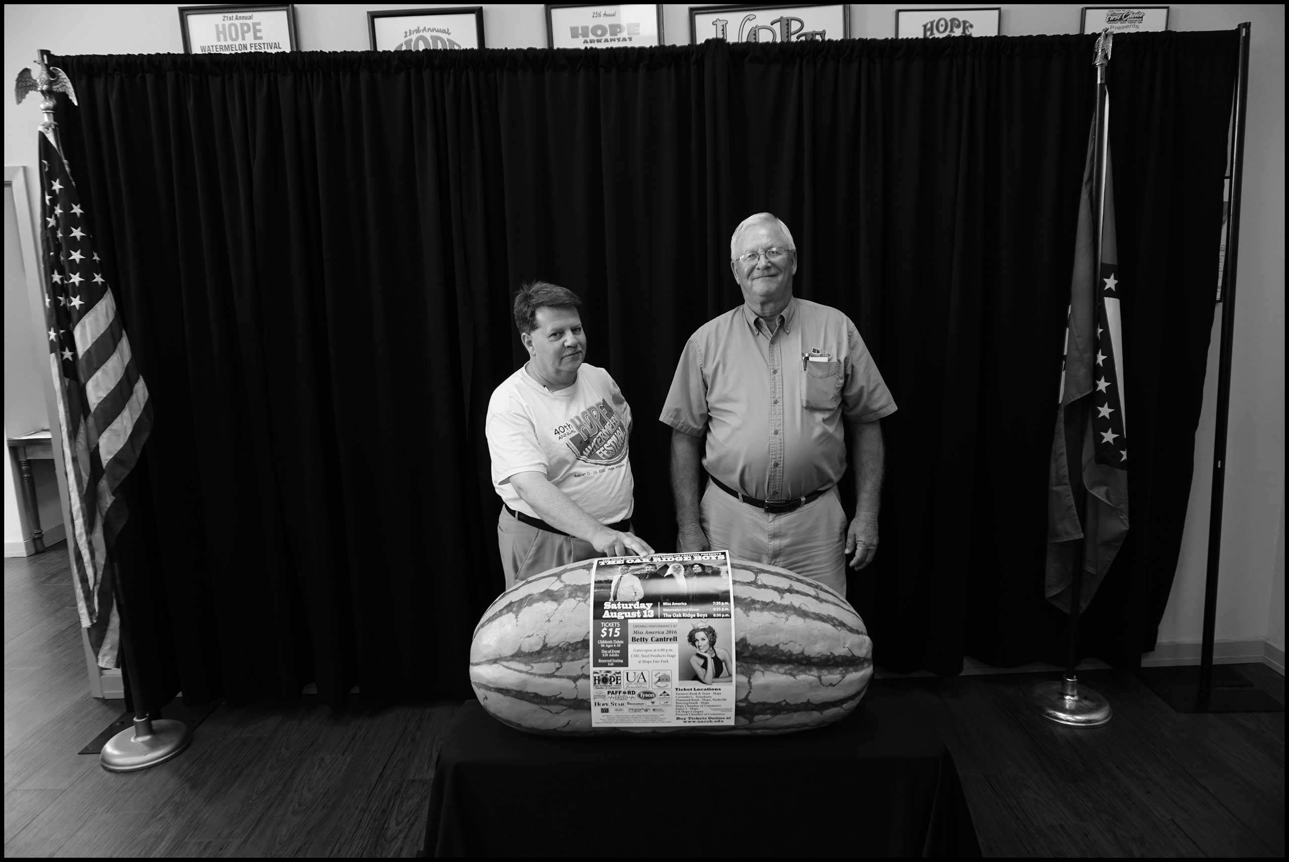 Portrait of Chamber of Commerce President Mark Keith 
                              and Wendell Hoover standing in front of replica of award winning watermelon in the Chamber of Commerce office. Hope, Ark. 2016.