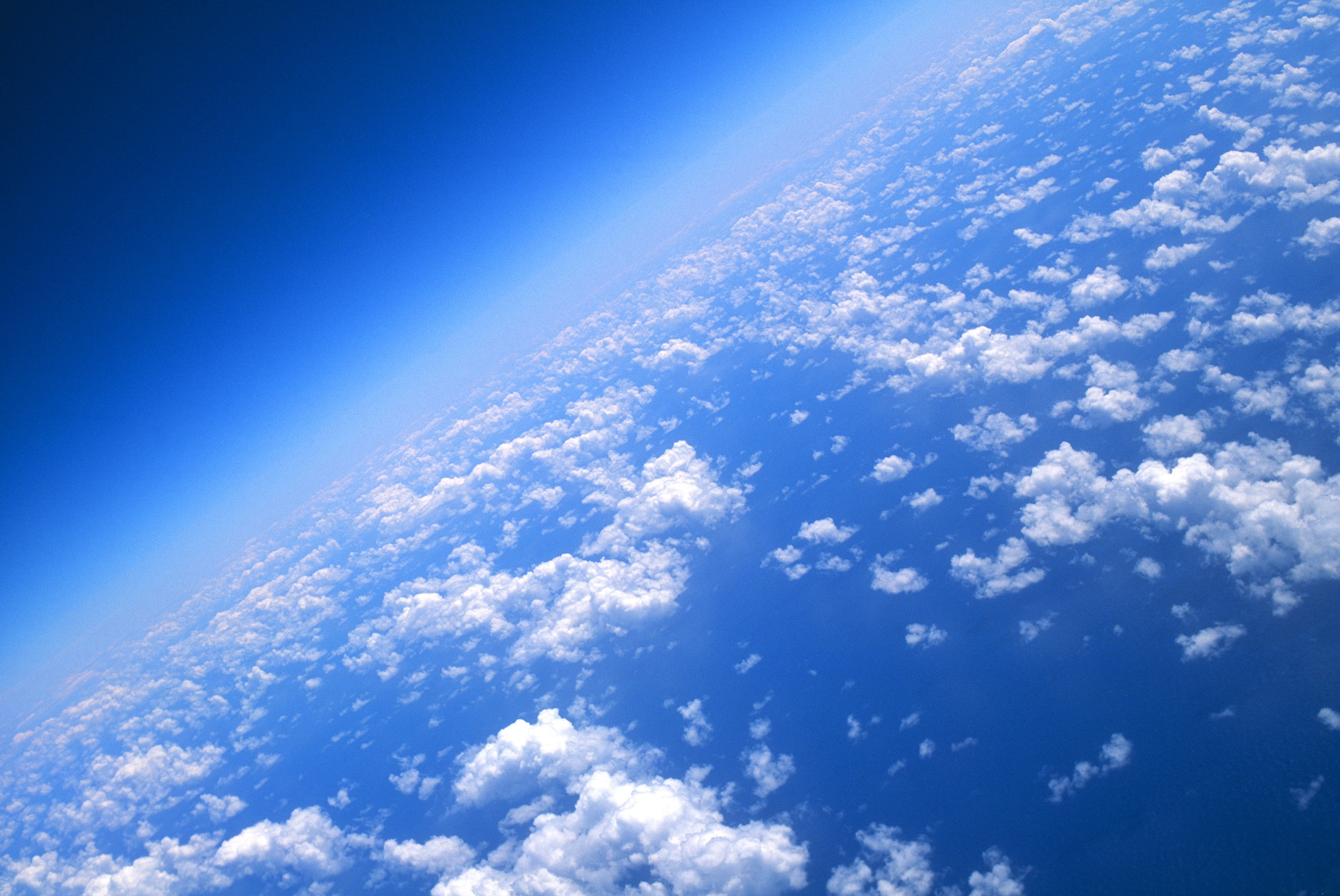 View of world from 40000 feet, clouds and blue sea.