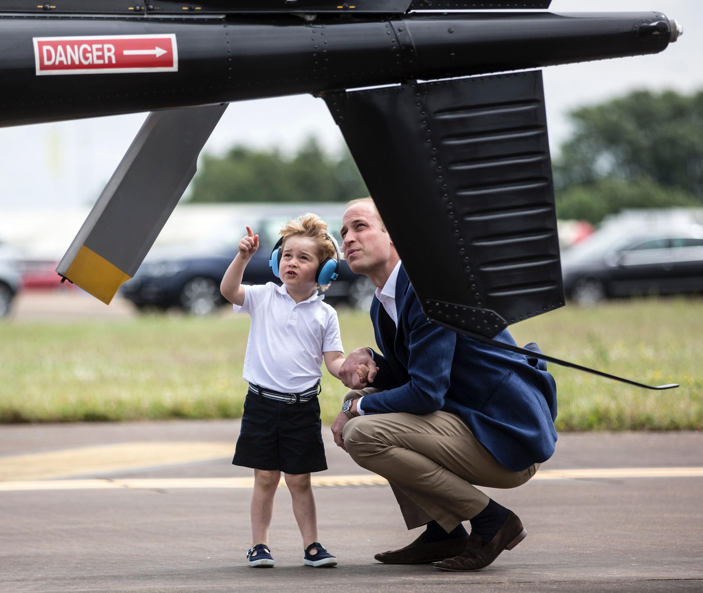 Britain's Prince George points as he and his father, Prince William, look at a 'Squirrel' helicopter during a visit to the Royal International Air Tattoo at RAF Fairford in western England on July 8, 2016.