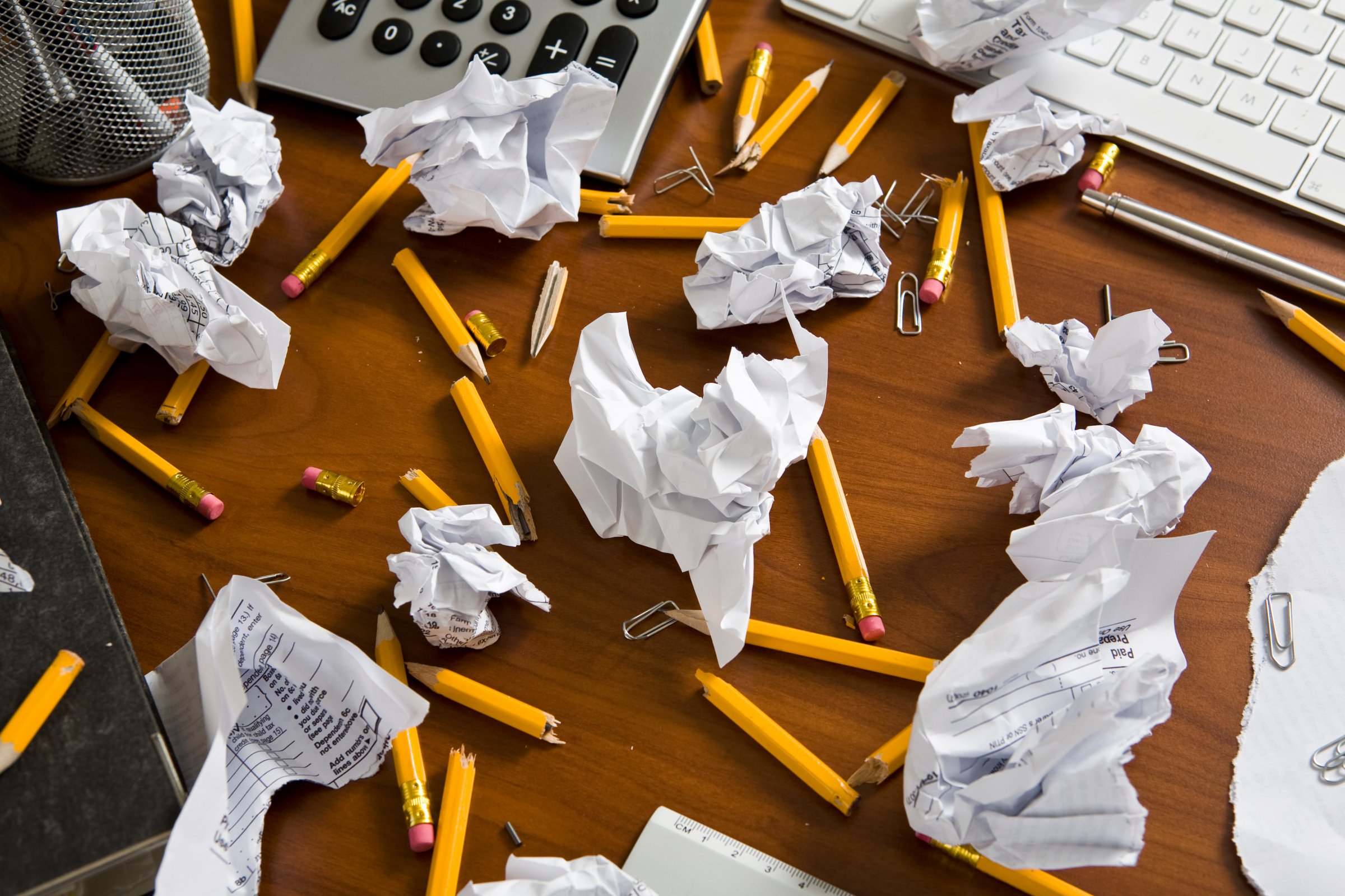 An office desk cluttered with pencils and crumpled paper