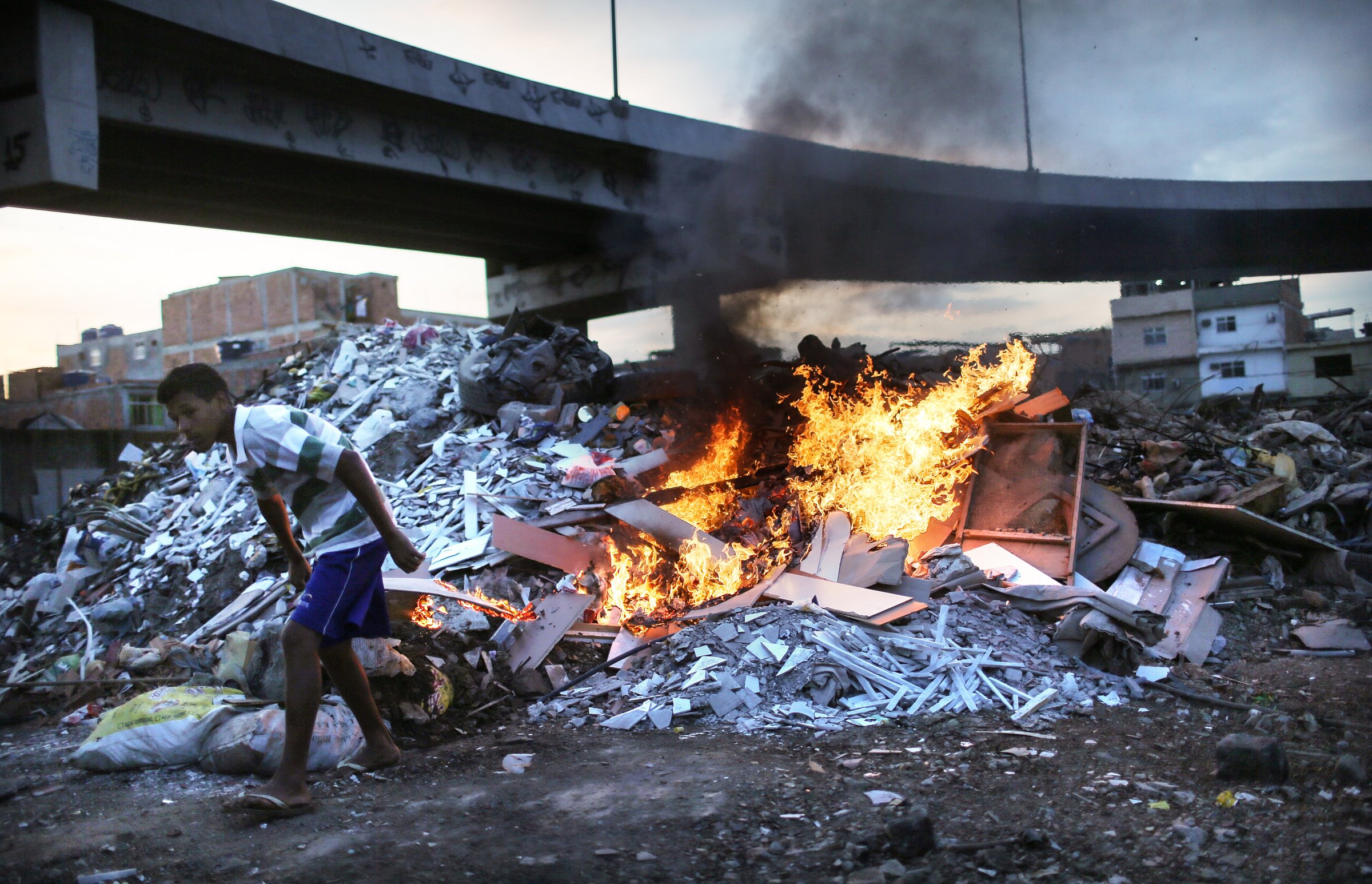 Trash is burned in an area where garbage is dumped near the main highway linking Rio's international airport to the city in the Mare favela community complex in Rio de Janeiro on July 18, 2016.