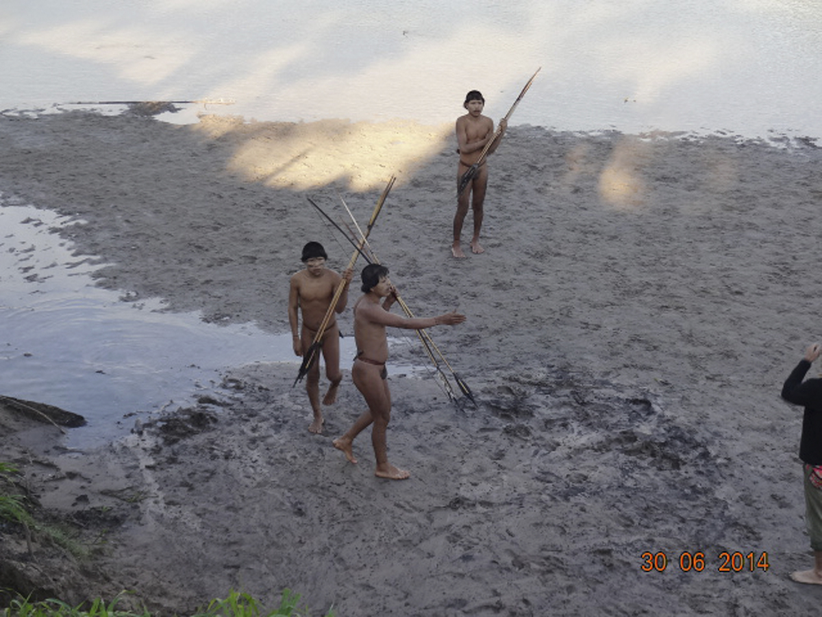 Three members of a previously uncontacted tribe make voluntary contact with a team of researchers, right, edge of photo, from Brazil's National Indian Foundation (FUNAI) on the bank of the Envira River in Aldeia Simpatia, Brazil, in this June 30, 2014, handout photo provided by FUNAI (Handout—Reuters)