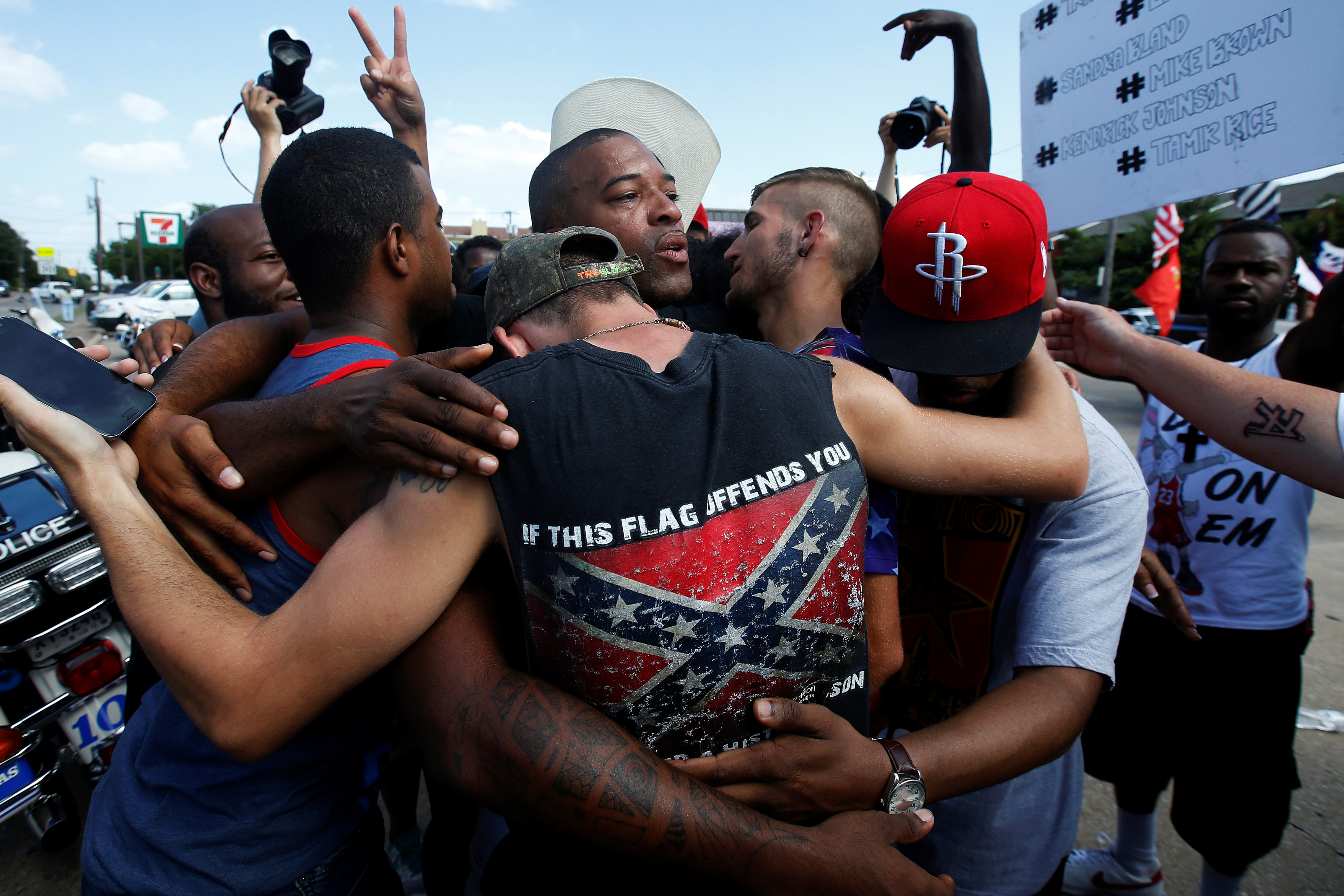 People, including a man wearing a confederate flag, hug after taking part in a prayer circle after a Black Lives Matter protest following the multiple police shootings in Dallas