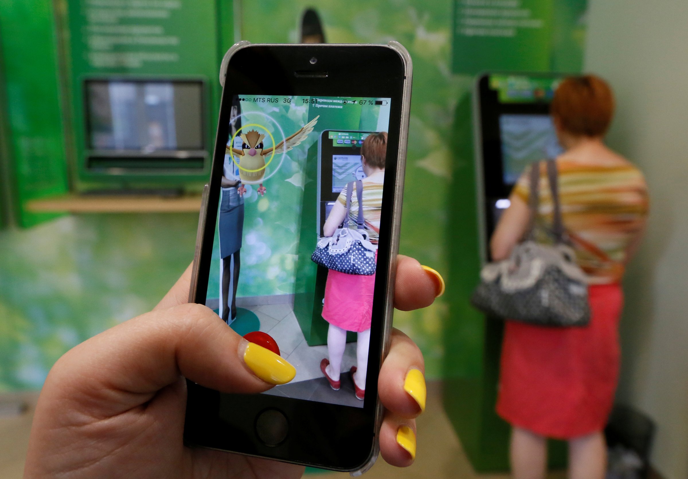 Woman plays augmented reality mobile game "Pokemon Go" by Nintendo at branch of Sberbank in central Krasnoyarsk